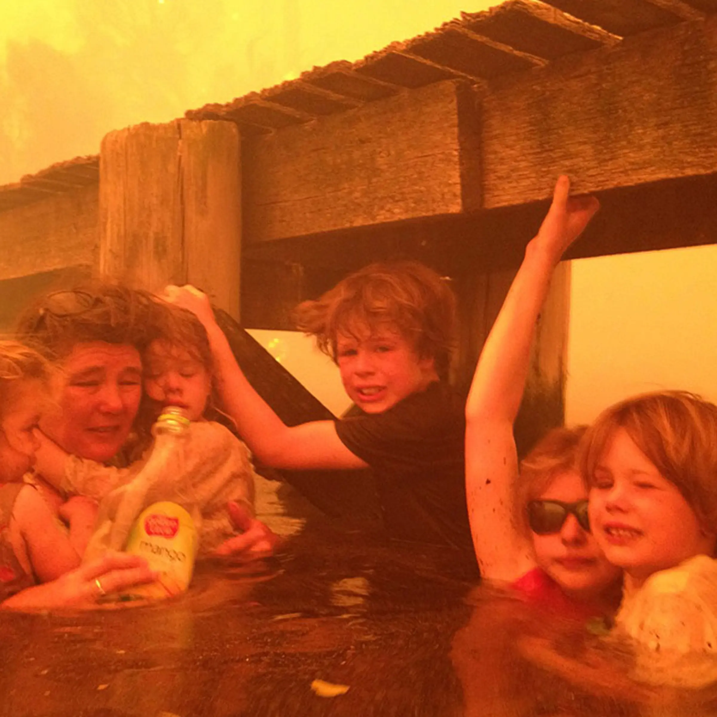 Jan. 4, 2013. Tammy Holmes, second from left, and her grandchildren, two-year-old Charlotte Walker, left, four-year-old Esther Walker, third from left, nine-year-old Liam Walker, eleven-year-old Matilda, second from right, and six-year-old Caleb Walker, right, take refuge under a jetty as a wildfire rages near-by in the Tasmanian town of Dunalley, Australia.