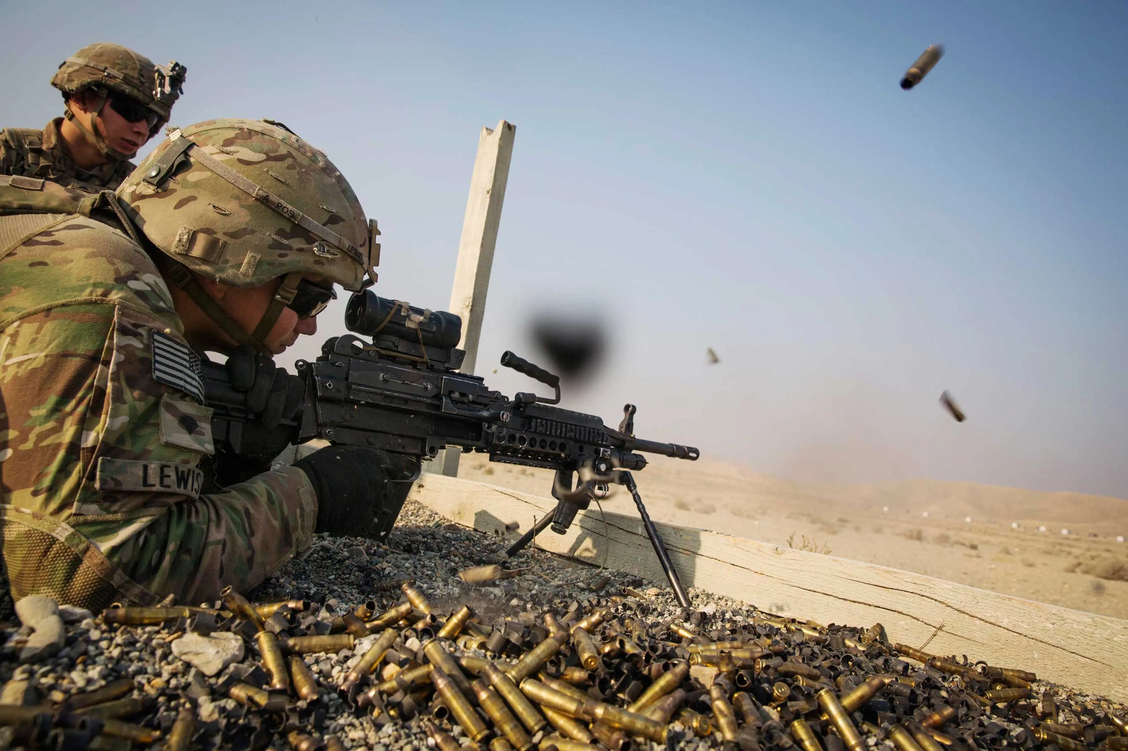 A U.S. soldier from the 3rd Cavalry Regiment is watched as he fires a squad automatic weapon during a training mission near forward operating base Gamberi, in the Laghman province of Afghanistan