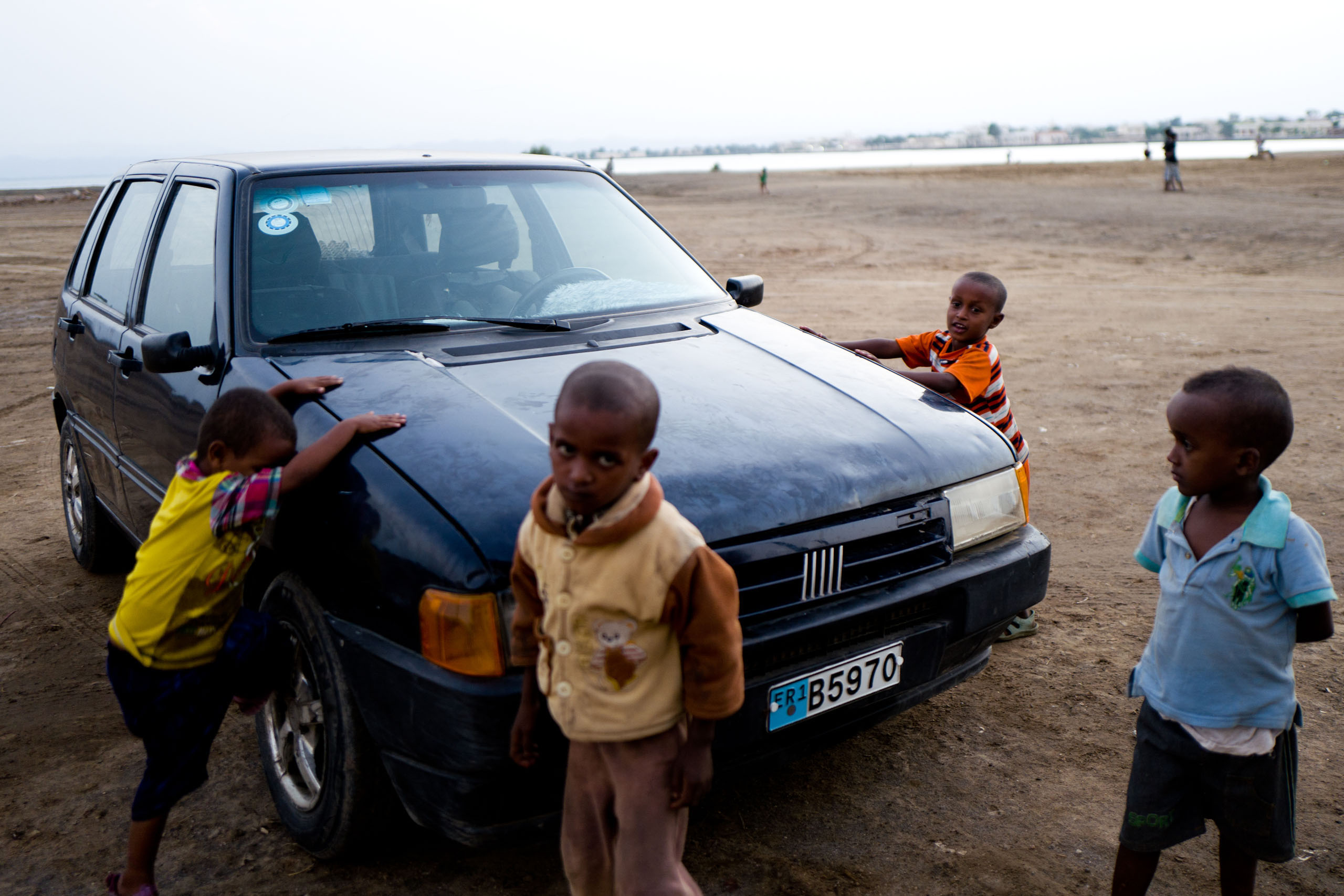 Children playing next to a Fiat Uno car on the streets of Massawa.