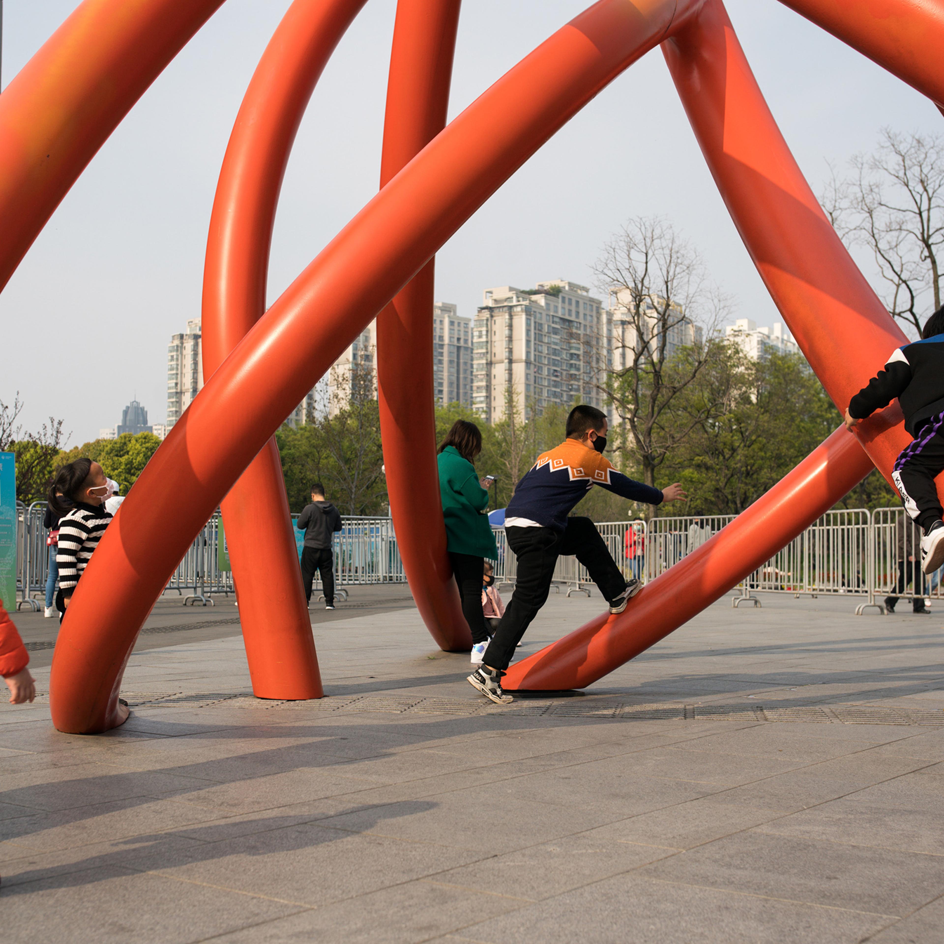 Children wear protective masks while playing under a sculpture in a city park on April 01, in Shanghai, China