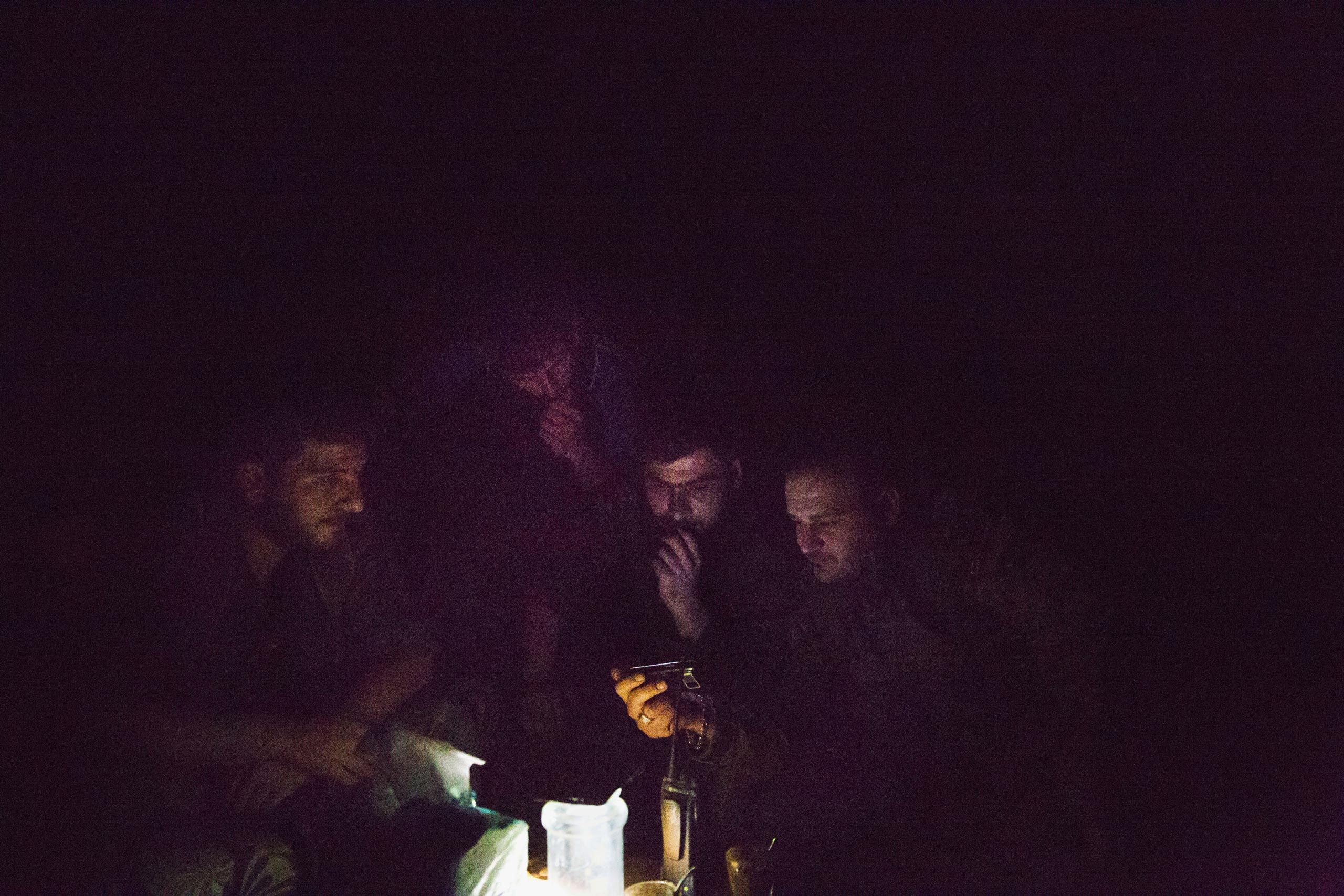 Deep inside the industrial district of Deir-ez Zor, close to known ISIS positions, fighters with the Syrian government's Directorate of Military Intelligence watch a video on a cellphone, May 16, 2015.
