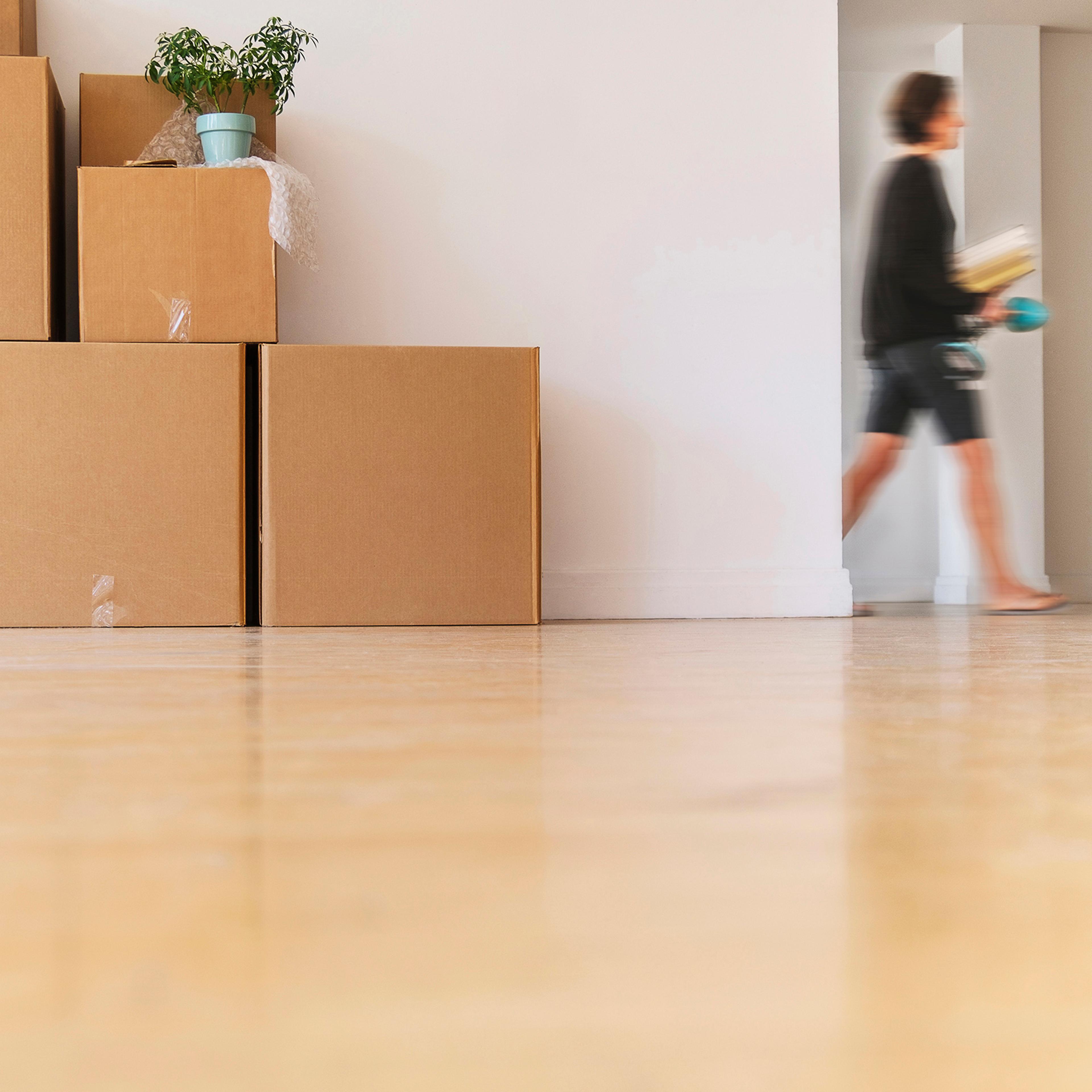 Woman walking near cardboard boxes stacked against wall