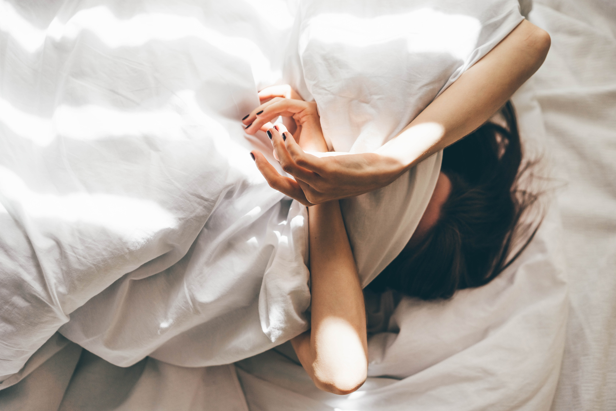 Sleepless Woman Lying In Bed Hiding Under Duvet.