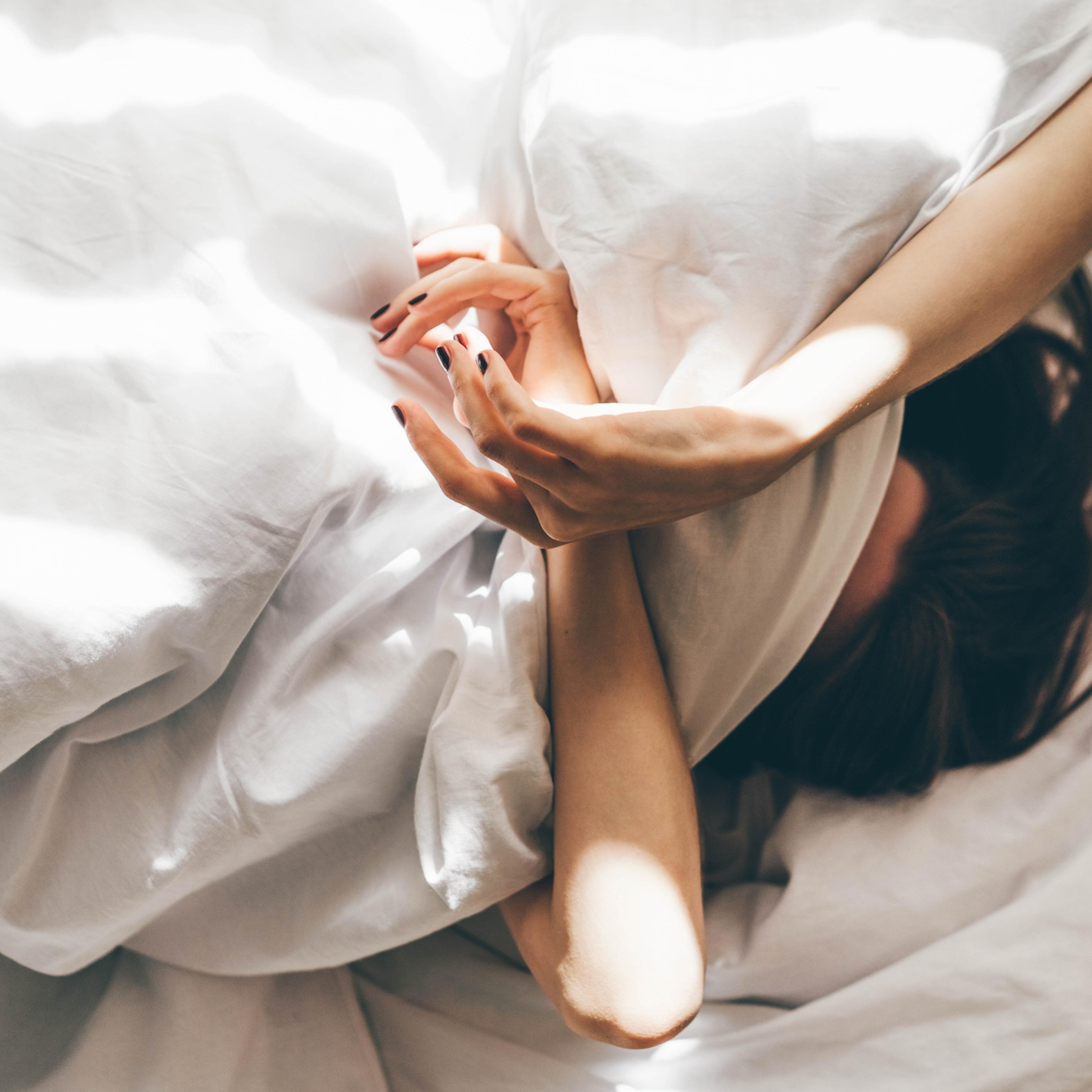 Sleepless Woman Lying In Bed Hiding Under Duvet.