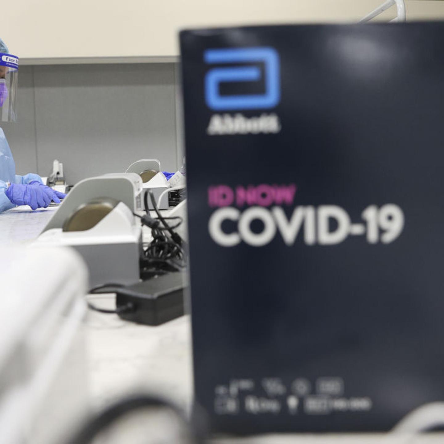A healthcare worker wearing personal protective equipment (PPE) uses a Abbott Laboratories ID NOW rapid test machine during a United Airlines COVID-19 test pilot program at Newark Liberty International Airport in Newark,
