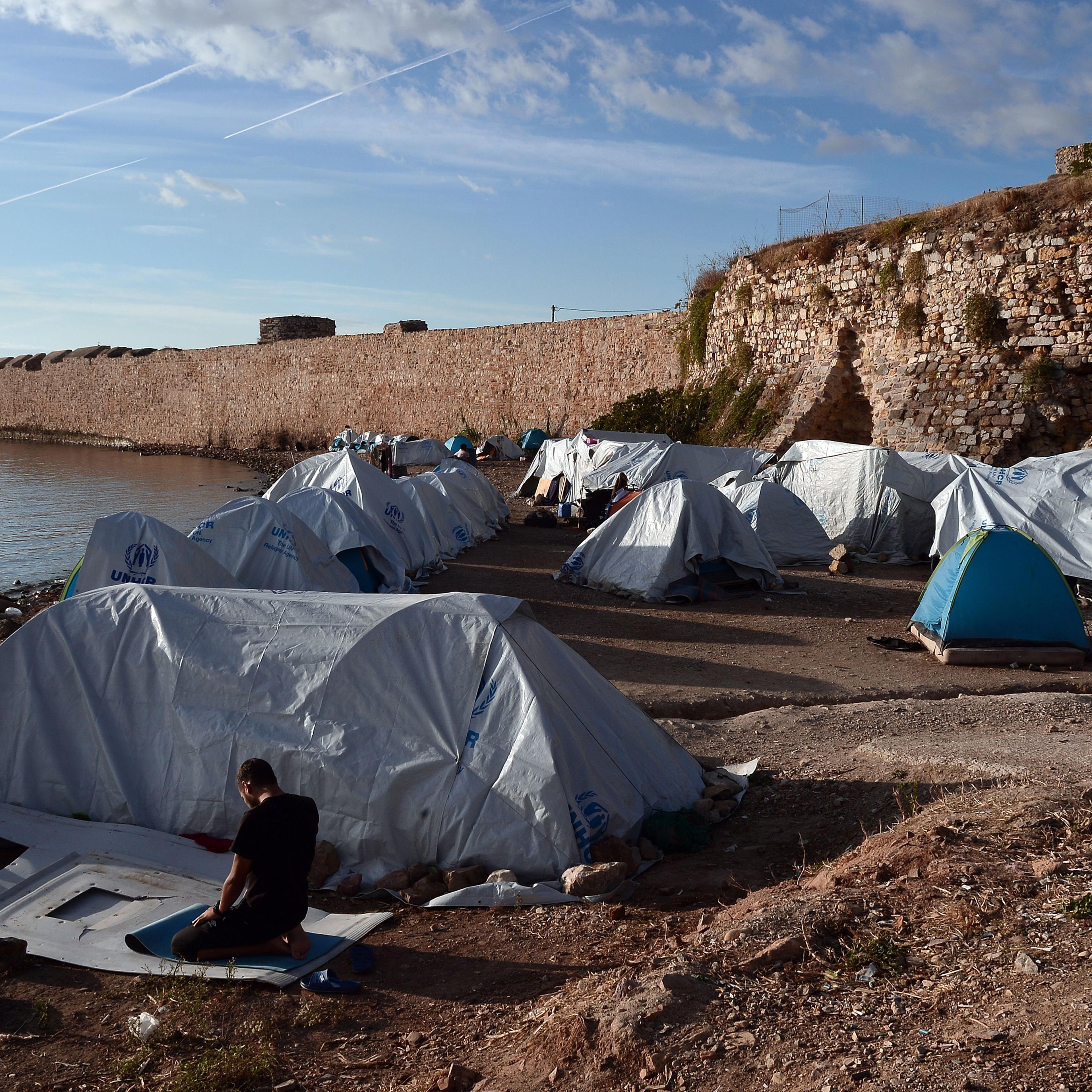 A man prays outside his tent set up on a beach at the Souda municipality-run refugee camp on the Greek island of Chios on October 13, 2016.