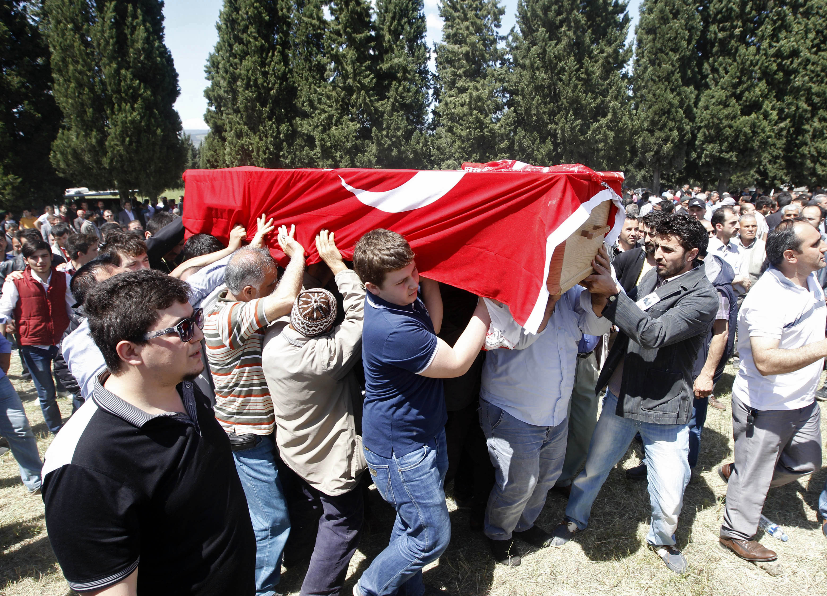 People carry the coffin of a miner who died in a fire at a coal mine, draped with a Turkish flag, during his funeral at a cemetery in Soma, a district in Turkey's western province of Manisa