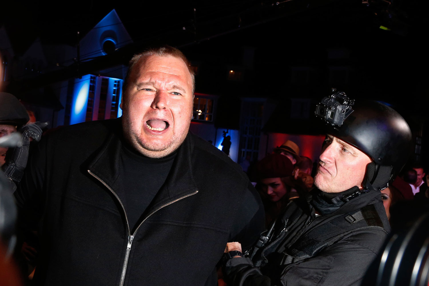 An actor in police costume mock-arrests Megaupload founder Kim Dotcom, left, as he launches his new file sharing site "Mega" in Auckland Jan. 20, 2013.