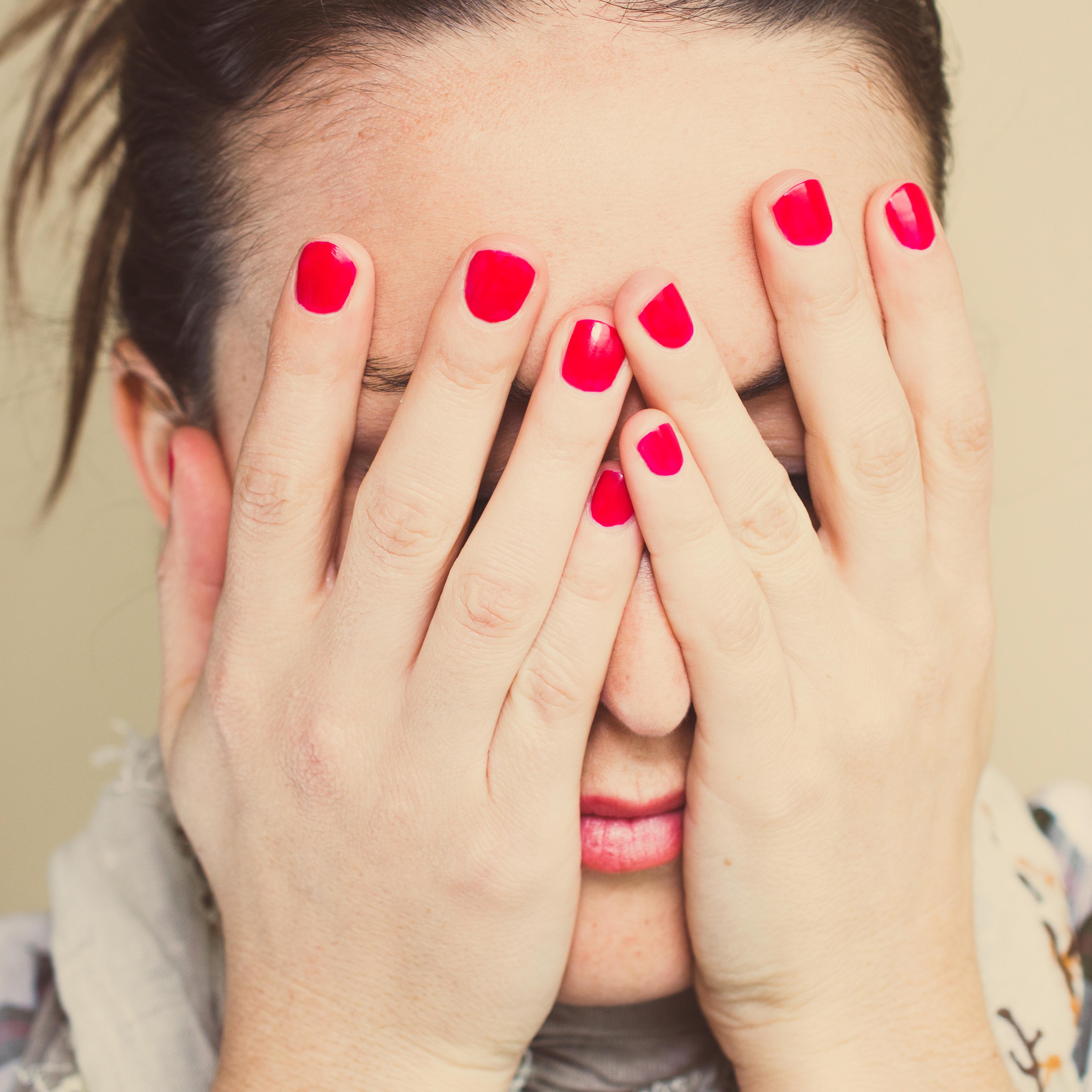Worried. Girl with hands on face and red nails