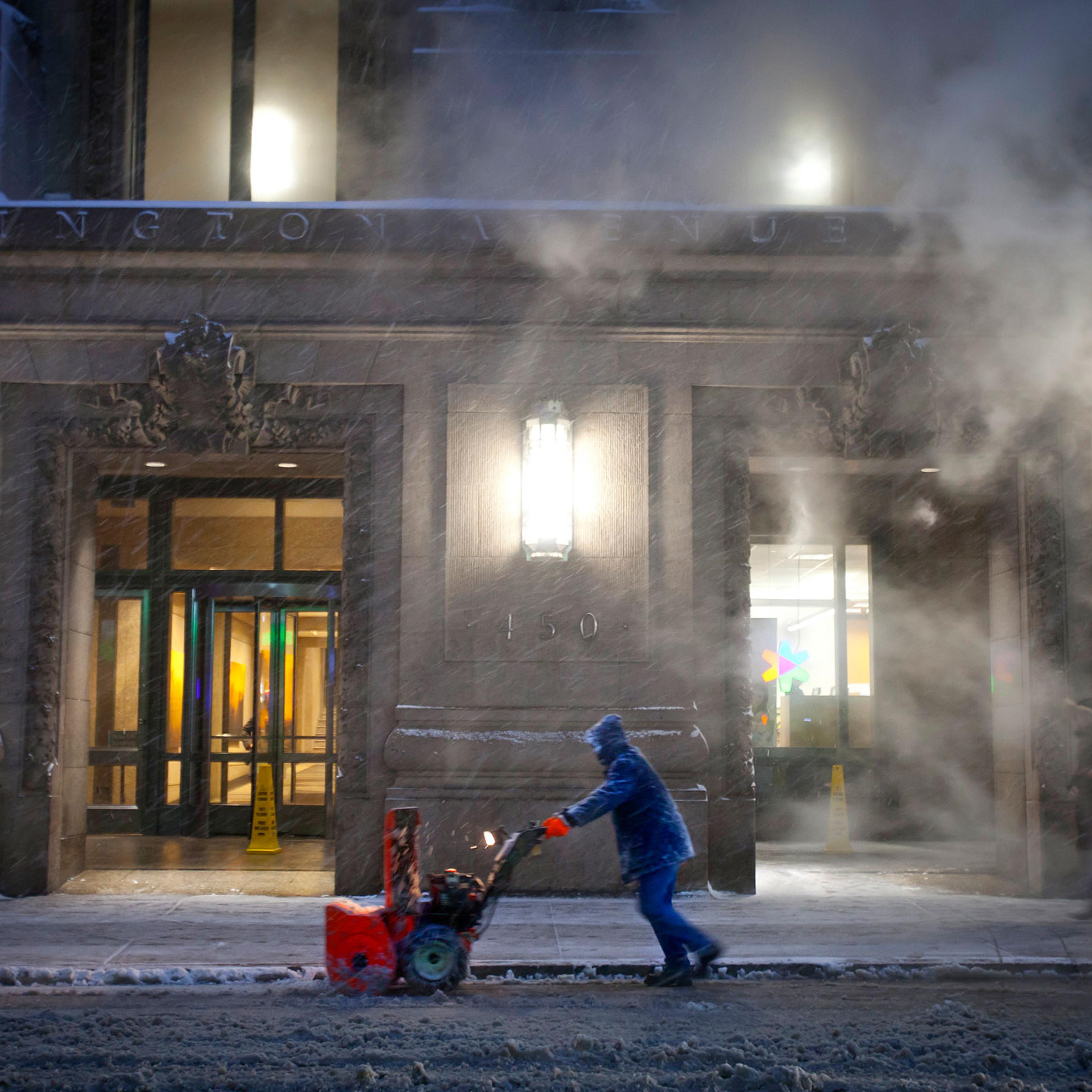 A worker pushes a snow blower down Lexington Avenue near Grand Central Terminal as it snows in the Manhattan borough of New York