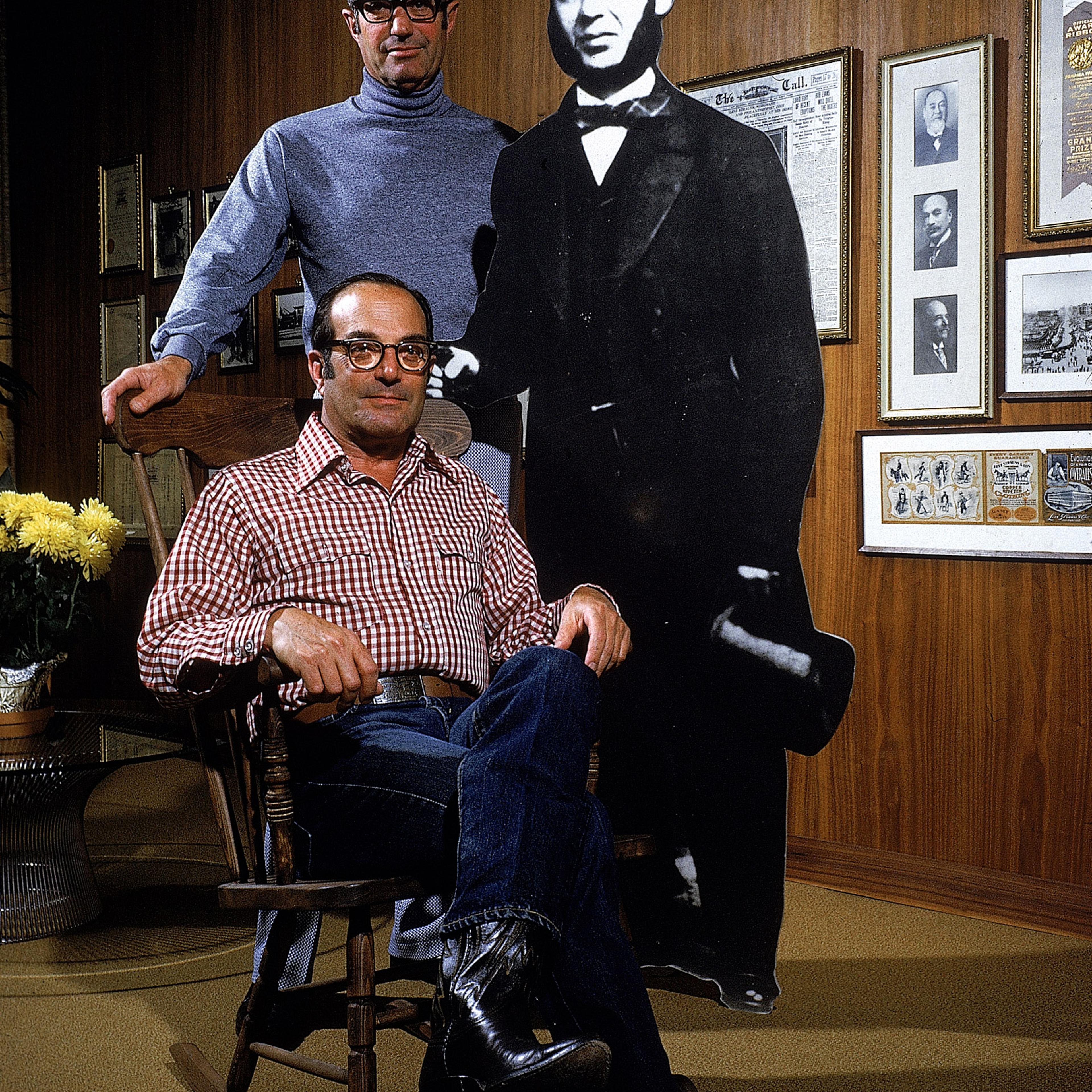 Peter Haas, President of Levi Strauss (seated) and former company president, his brother Walter (standing), next to cut-out of company founder, 1972.