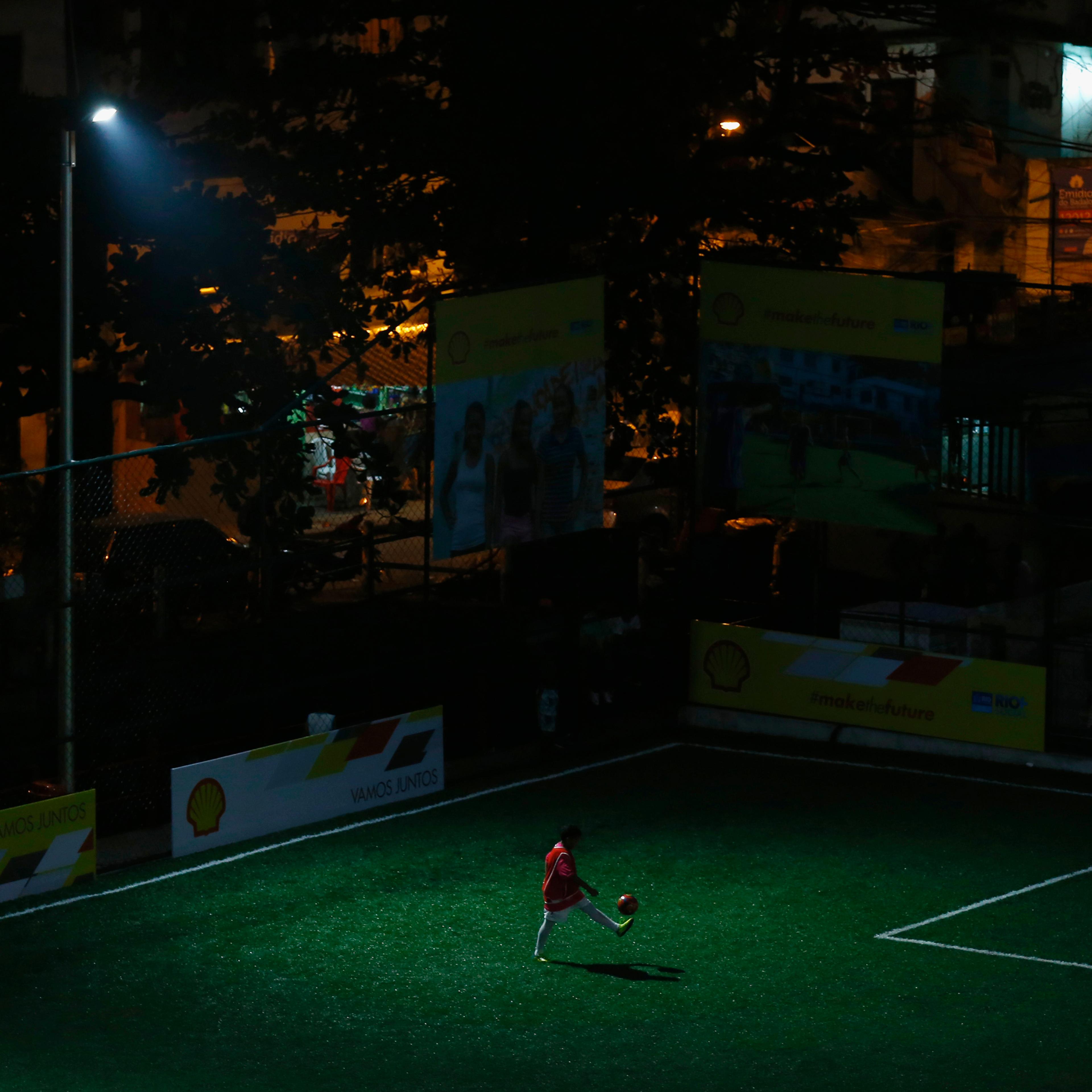 Kid plays with soccer ball at a refurbished soccer field at the Mineira slum in Rio de Janeiro