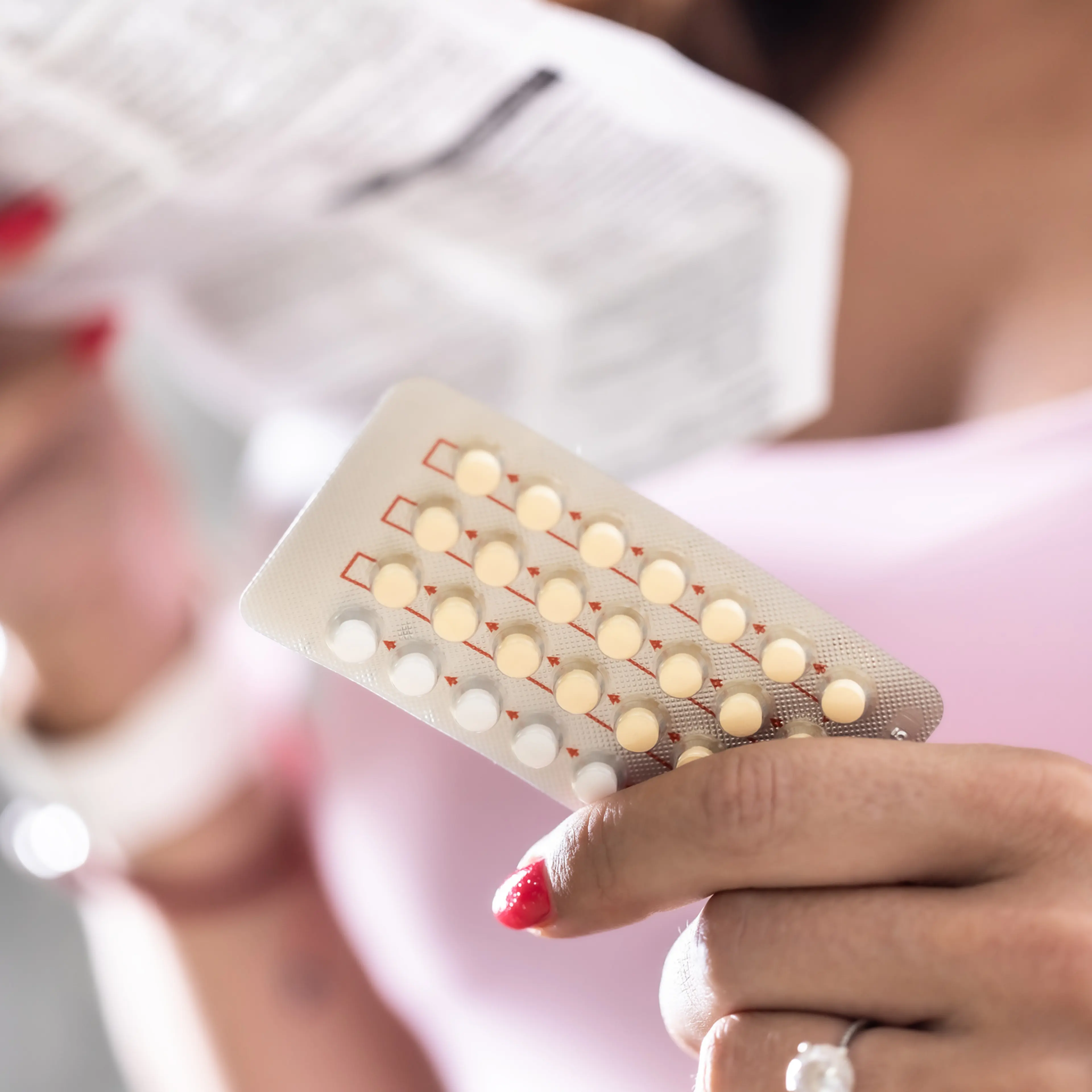 The woman holds contraceptive pills in one hand and instructions for use in the other