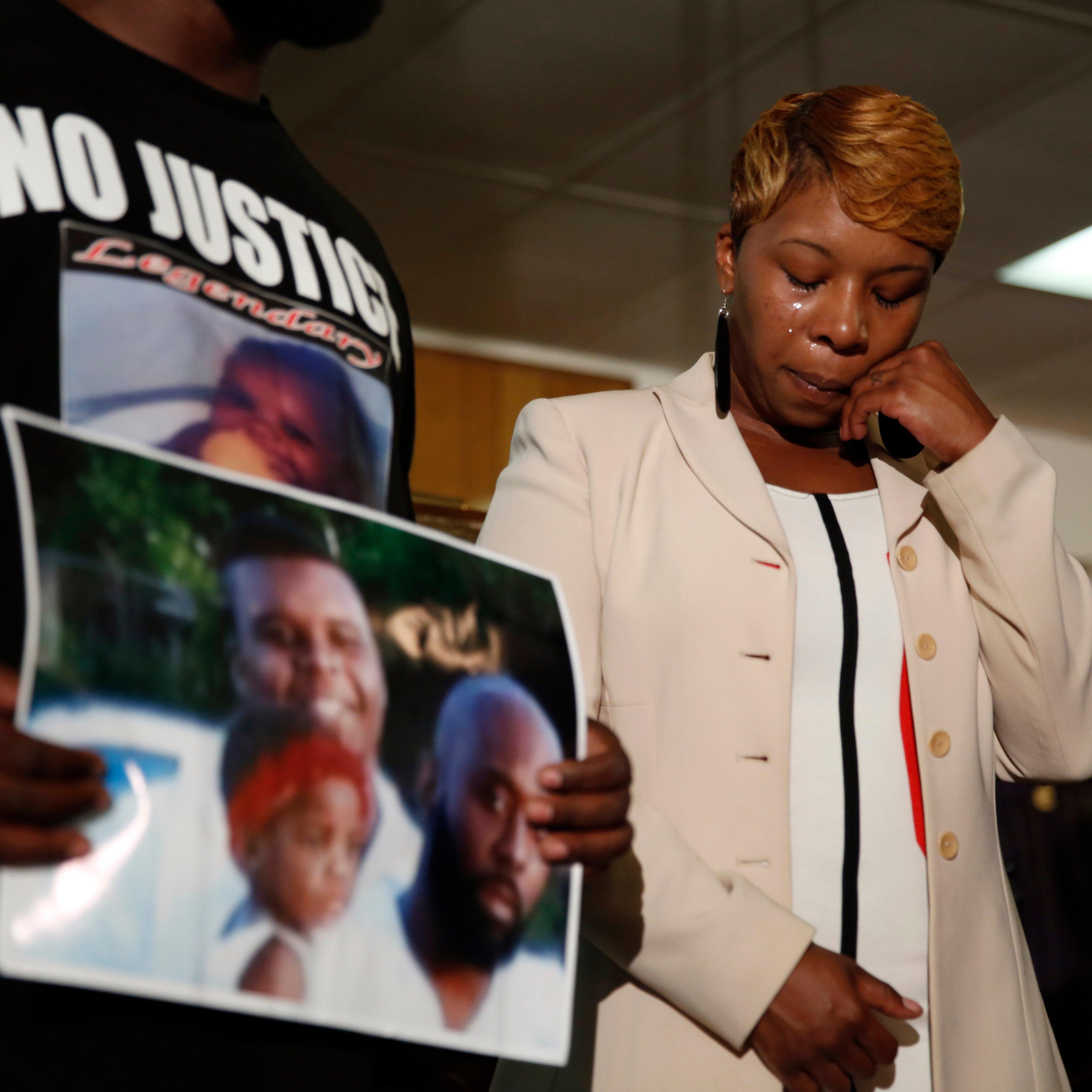 Lesley McSpadden, the mother of 18-year-old Michael Brown, wipes away tears as Brown's father, Michael Brown Sr., holds up a family picture of himself and his son during a news conference on August 11, 2014, in Ferguson, Mo.