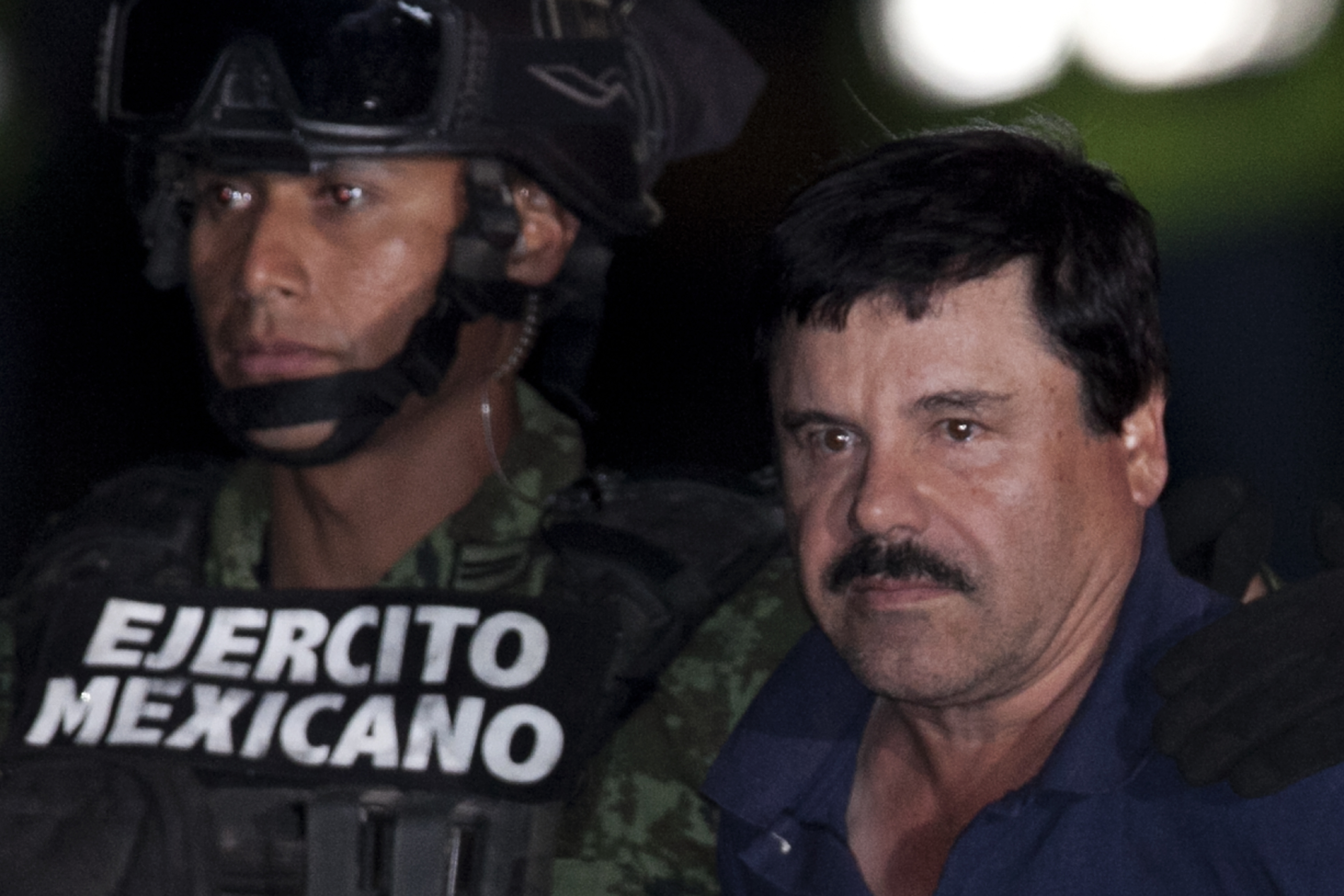 Mexican drug lord Joaquin "El Chapo" Guzman (r.) is escorted by soldiers and marines to a waiting helicopter, at a federal hangar in Mexico City on Jan. 8, 2016.