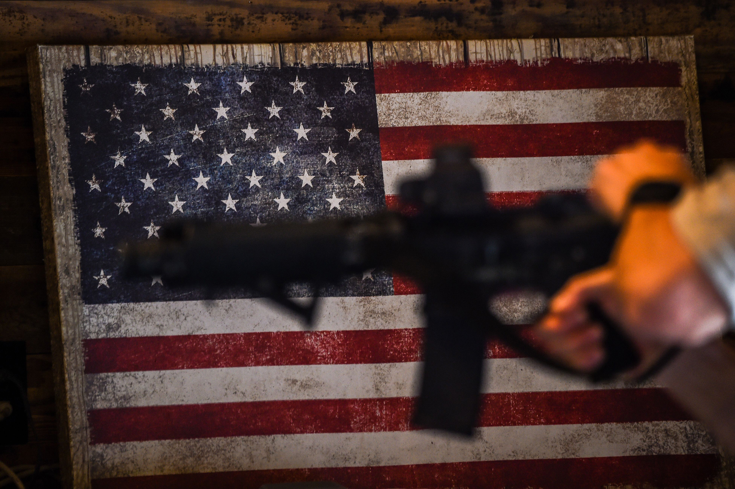 An instructor teaches handling of AR-15 semi-automatic rifles with a US flag in the background during a shooting course at Boondocks Firearms Academy in Jackson, Miss. on Sept. 26