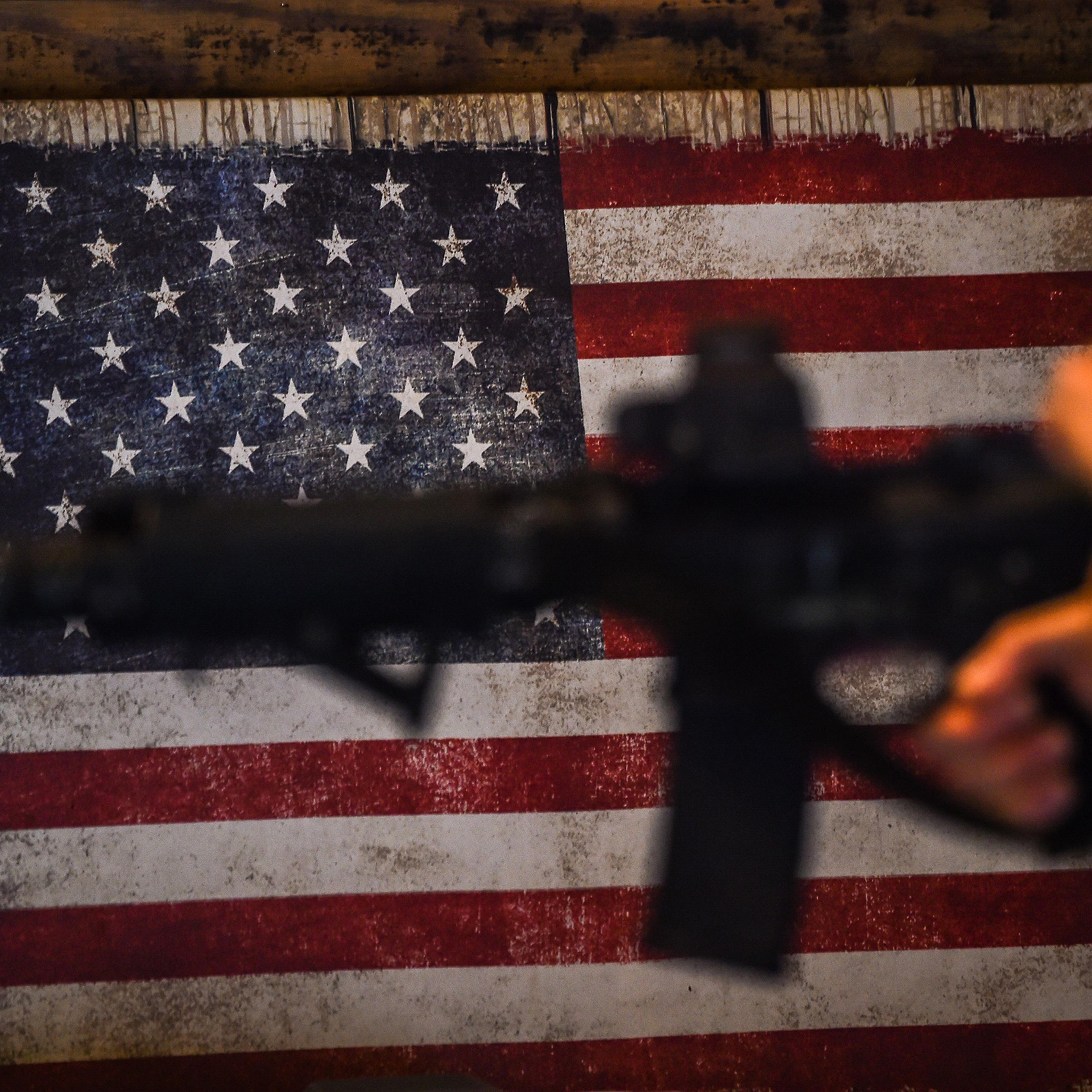 An instructor teaches handling of AR-15 semi-automatic rifles with a US flag in the background during a shooting course at Boondocks Firearms Academy in Jackson, Miss. on Sept. 26