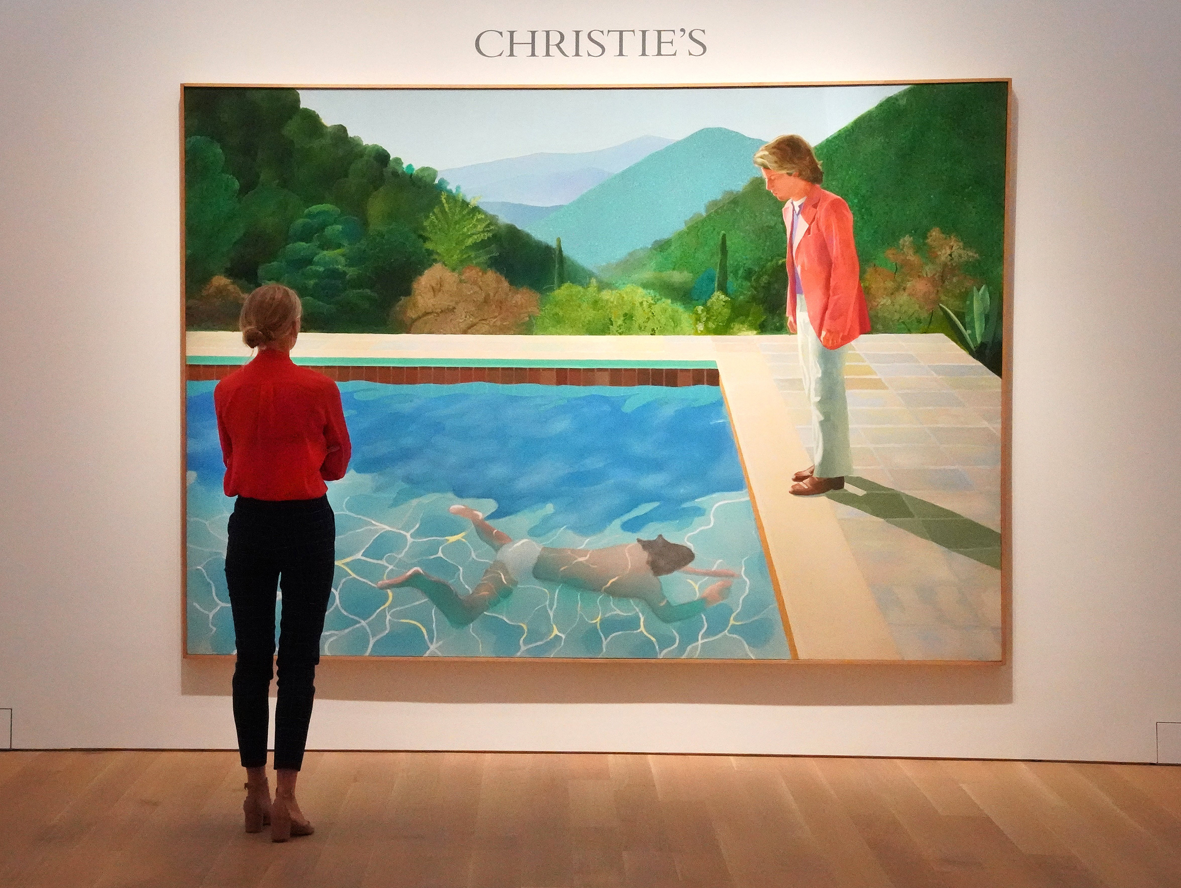 A woman looks at David Hockneys "Portrait of an Artist (Pool with Two Figures)" during a press preview on September 13, 2018 at Christie's New York. - The painting is to be auctioned during Christie's November 2018 Evening Sale of Post-War and Contempora