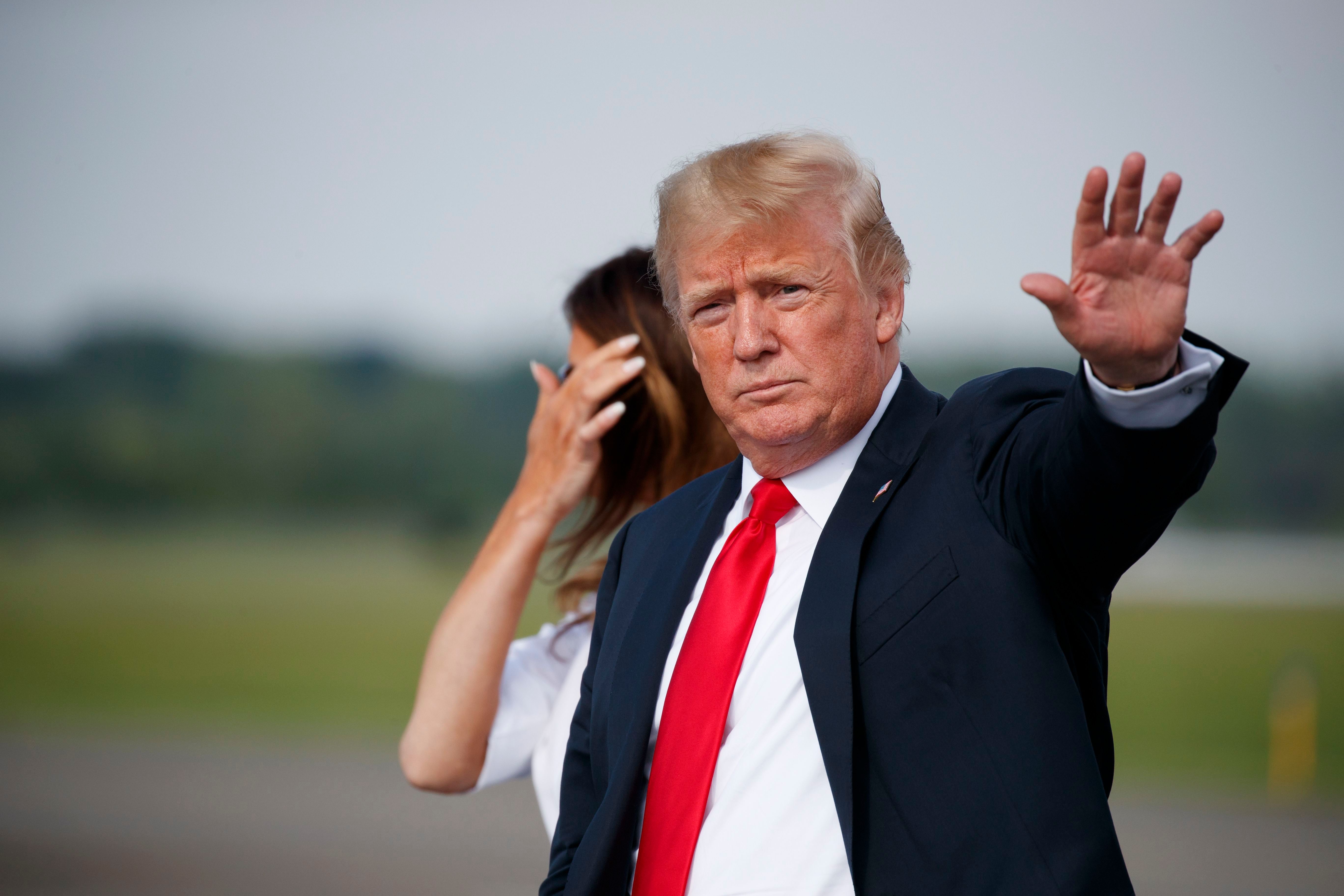 Trump waves to the press after getting off Air Force One