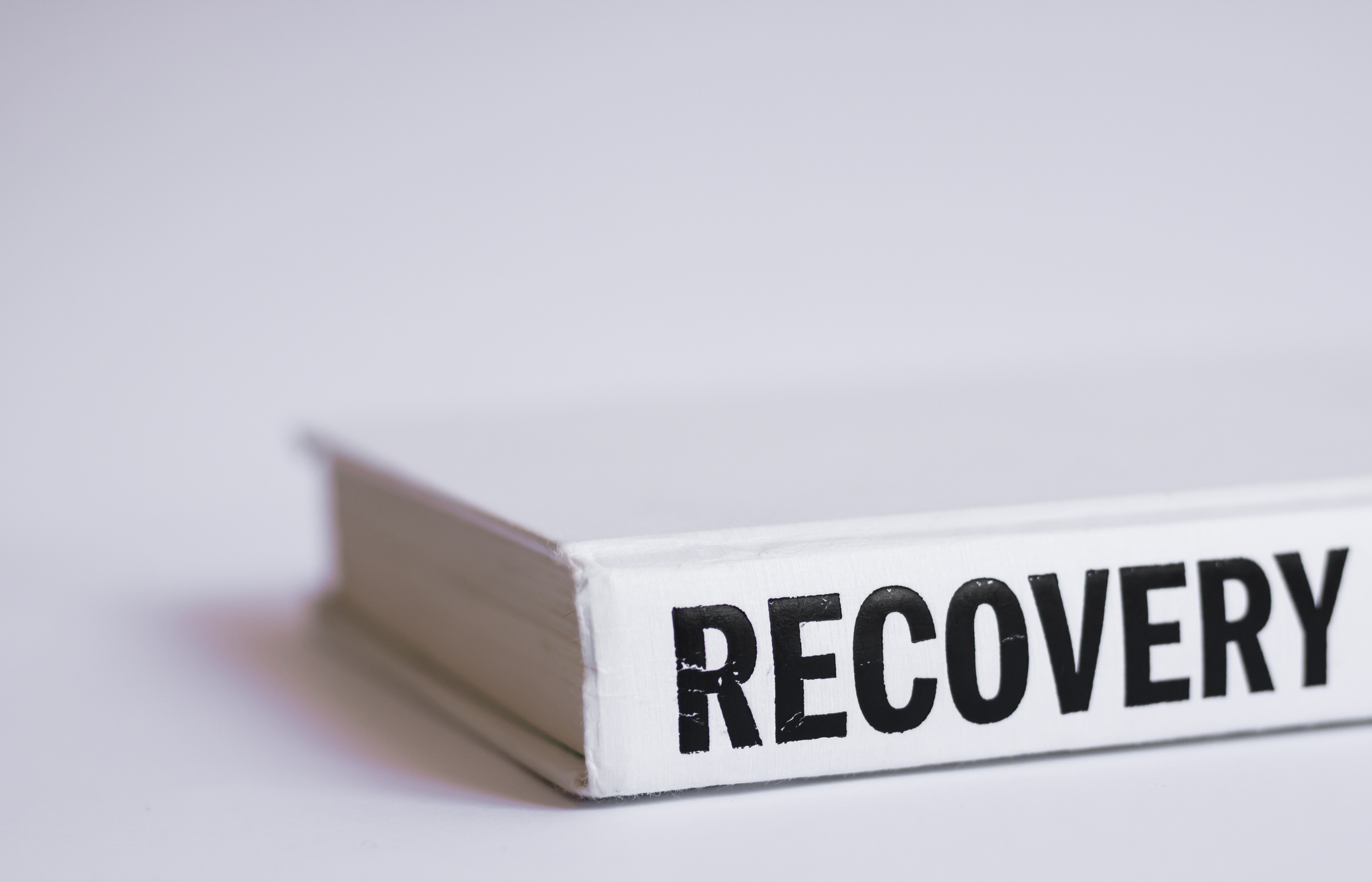 White book with black letters word Recovery written on it