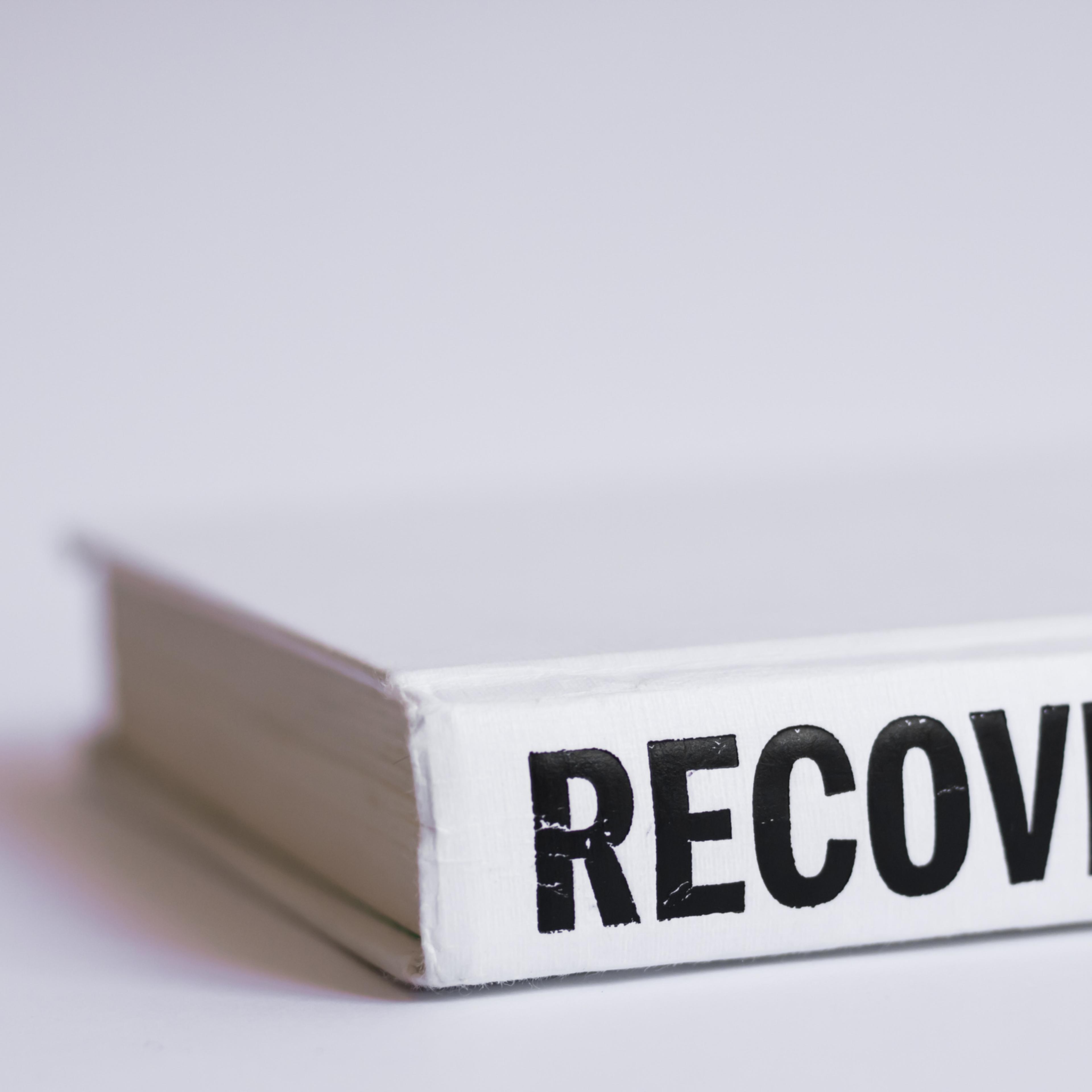 White book with black letters word Recovery written on it