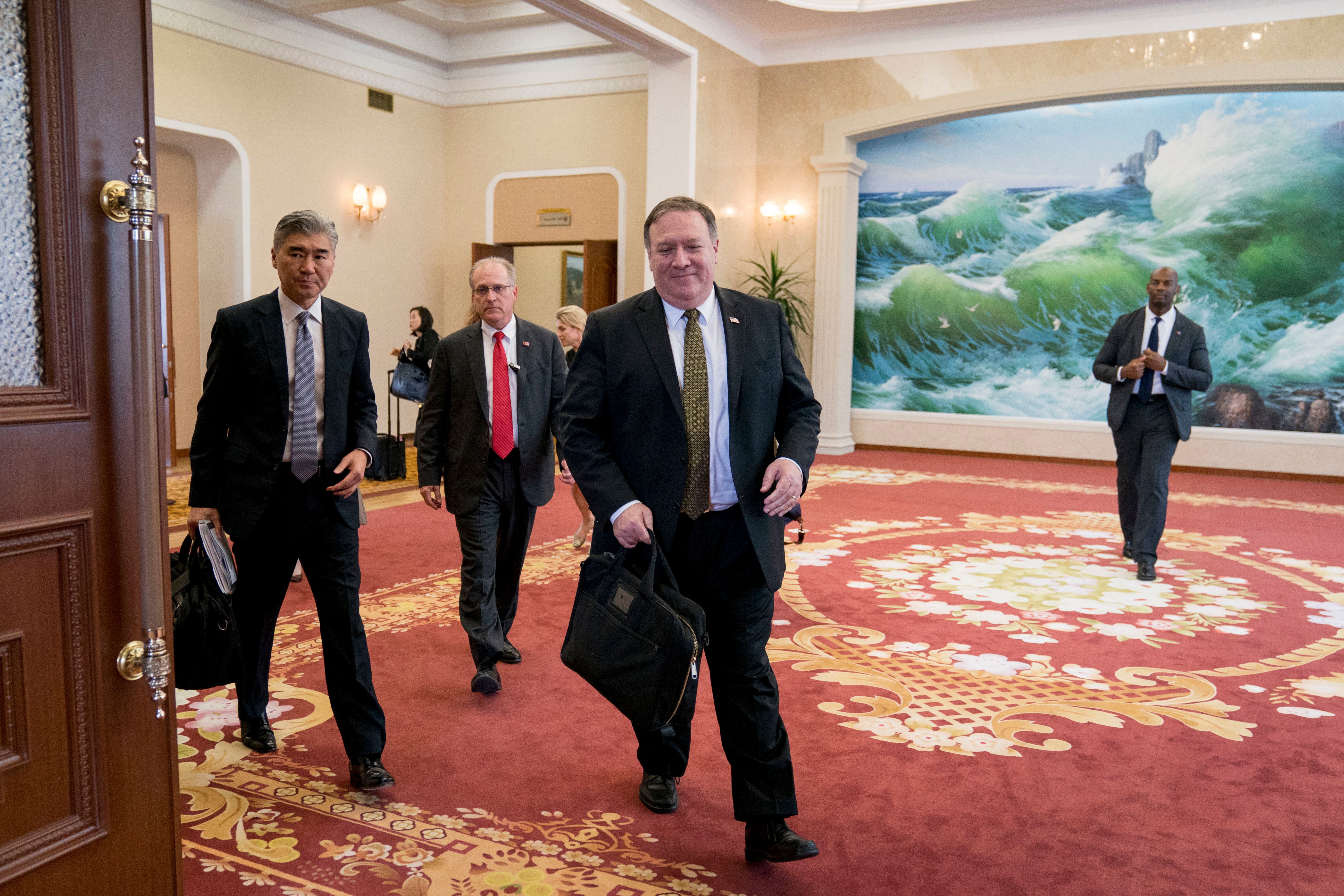 Michael Pompeo in a Guest House with three other men behind him. The carpet is red and there's a painting on the opposite wall