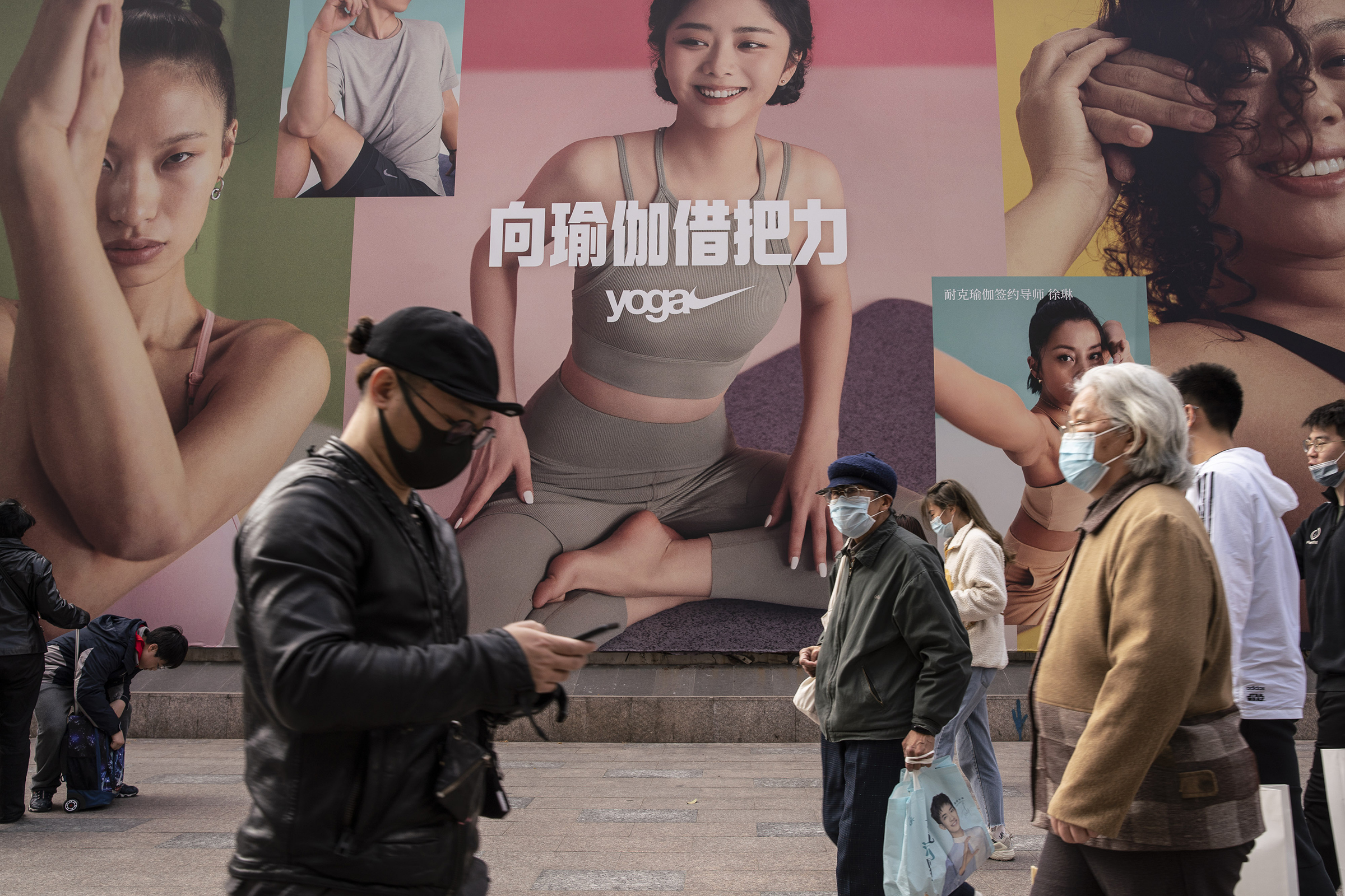 Pedestrians walk past a Nike yoga advertisement in Shanghai on March 26. China this week has pushed a campaign to boycott Western retailers after the U.S., U.K., Canada and the E.U. imposed sanctions over human-rights abuses against ethnic minority Uyghu
