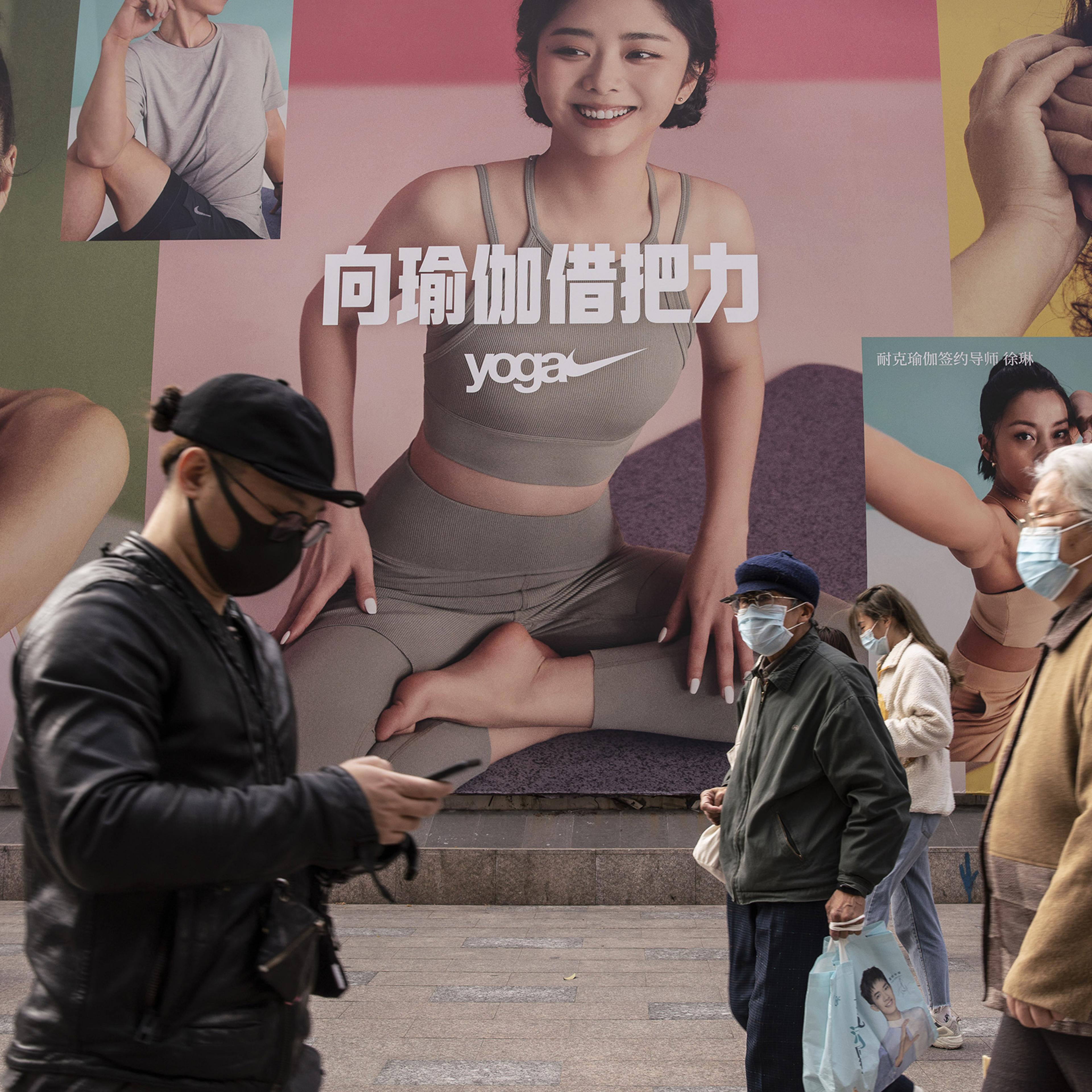 Pedestrians walk past a Nike yoga advertisement in Shanghai on March 26. China this week has pushed a campaign to boycott Western retailers after the U.S., U.K., Canada and the E.U. imposed sanctions over human-rights abuses against ethnic minority Uyghu