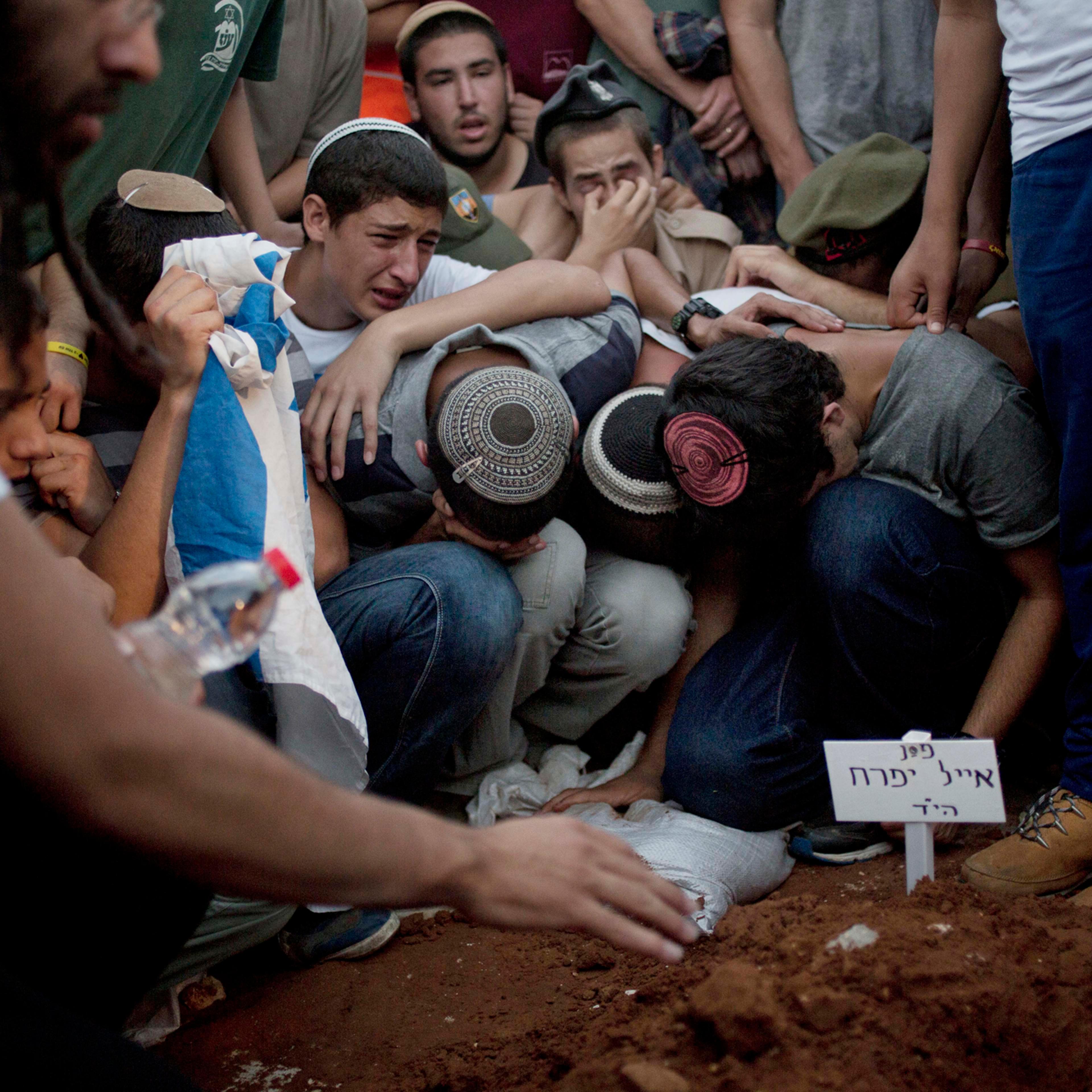 Family and friends of Eyal Yifrah, Gilad Shaar, and Naftali Fraenkel , three Israeli teenagers who were abducted over two weeks ago mourn over the grave of Eyal Yifrah during their funeral in Modiin, Israel, July 1.