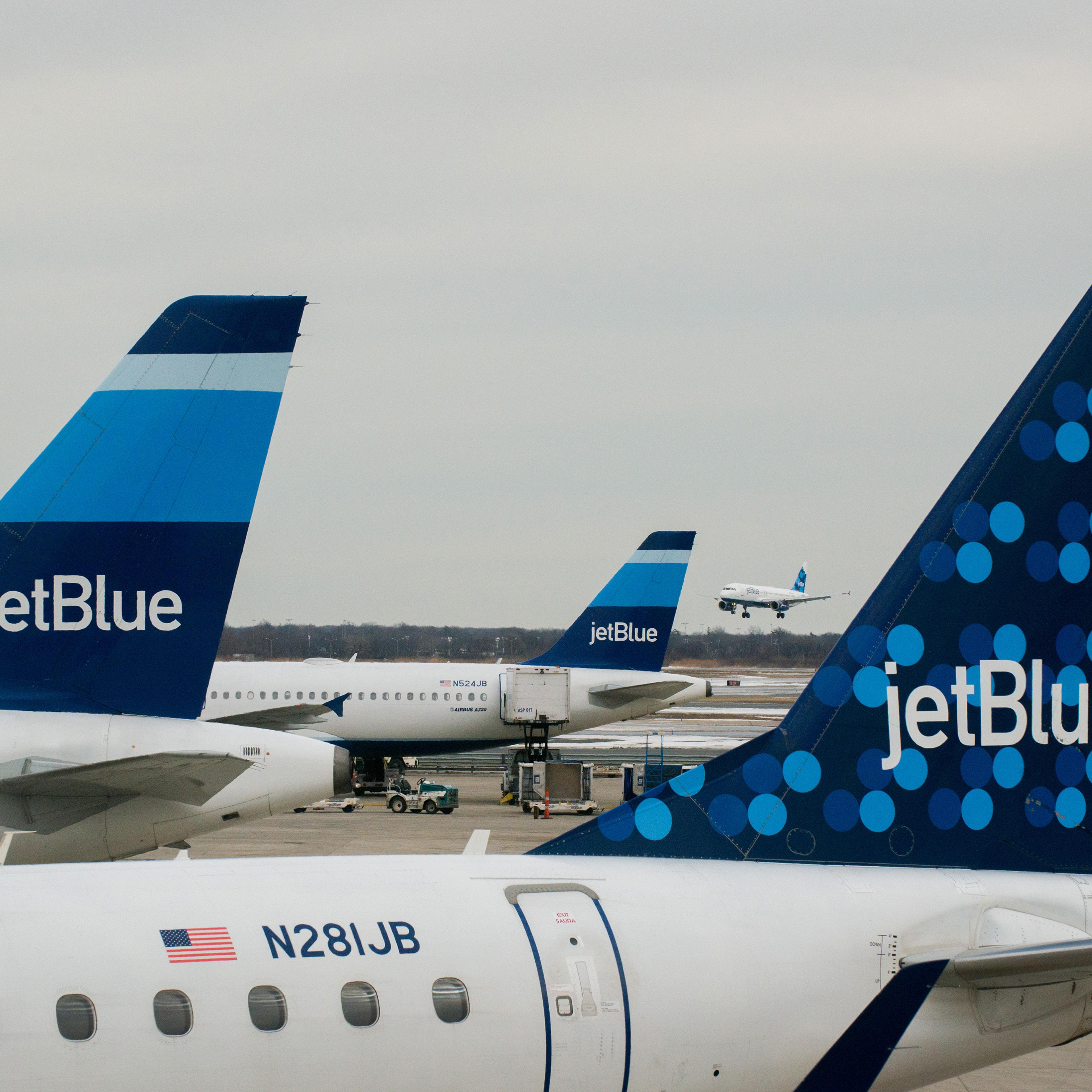 JetBlue Airways Corp. planes sit docked at the gates of Terminal 5 as another of the company's jets lands at John F. Kennedy International Airport in New York on Jan. 28, 2014.
