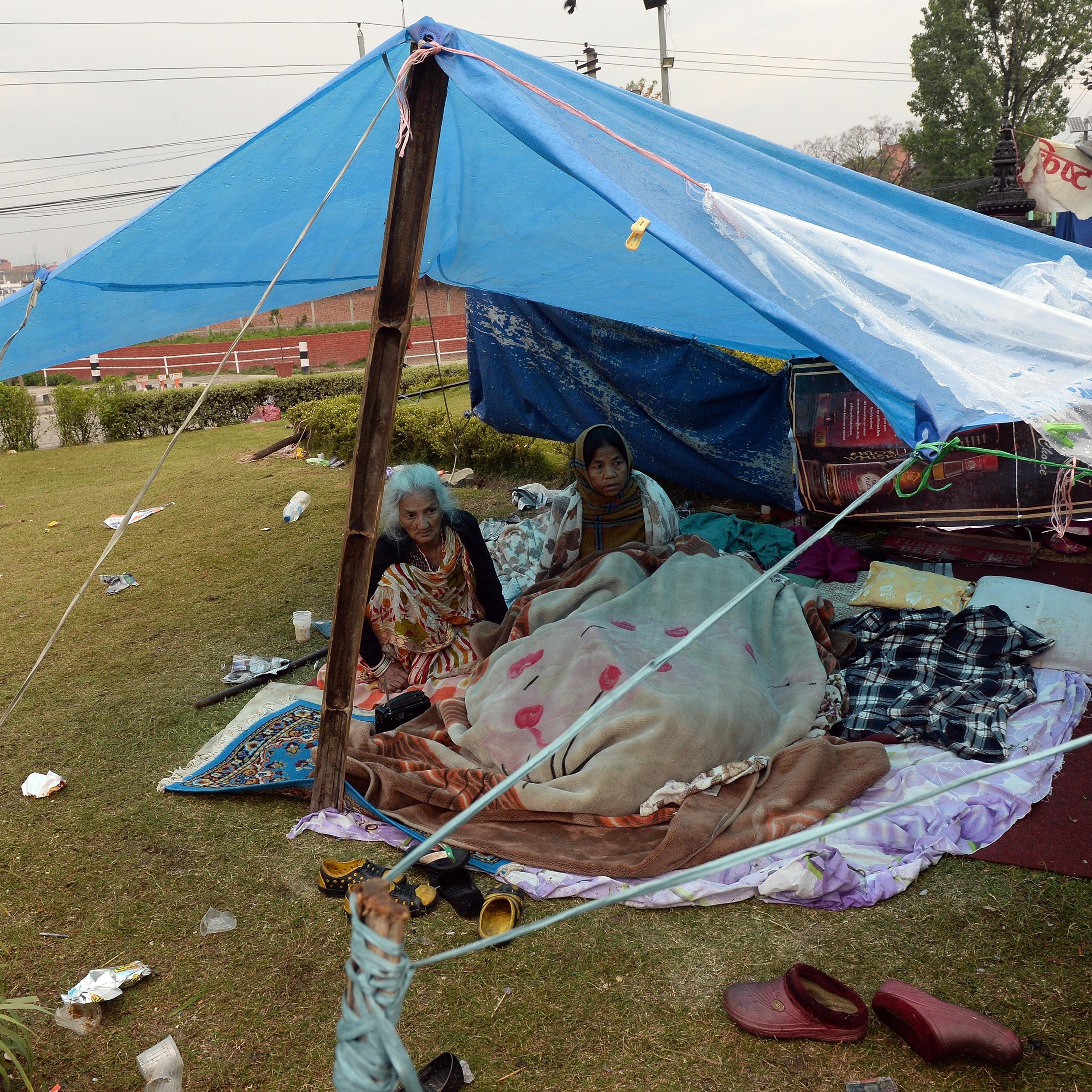 Nepalese people rest in their makeshift shelter next to a road in Kathmandu on April 27, 2015, two days after a 7.8 magnitude earthquake hit Nepal.