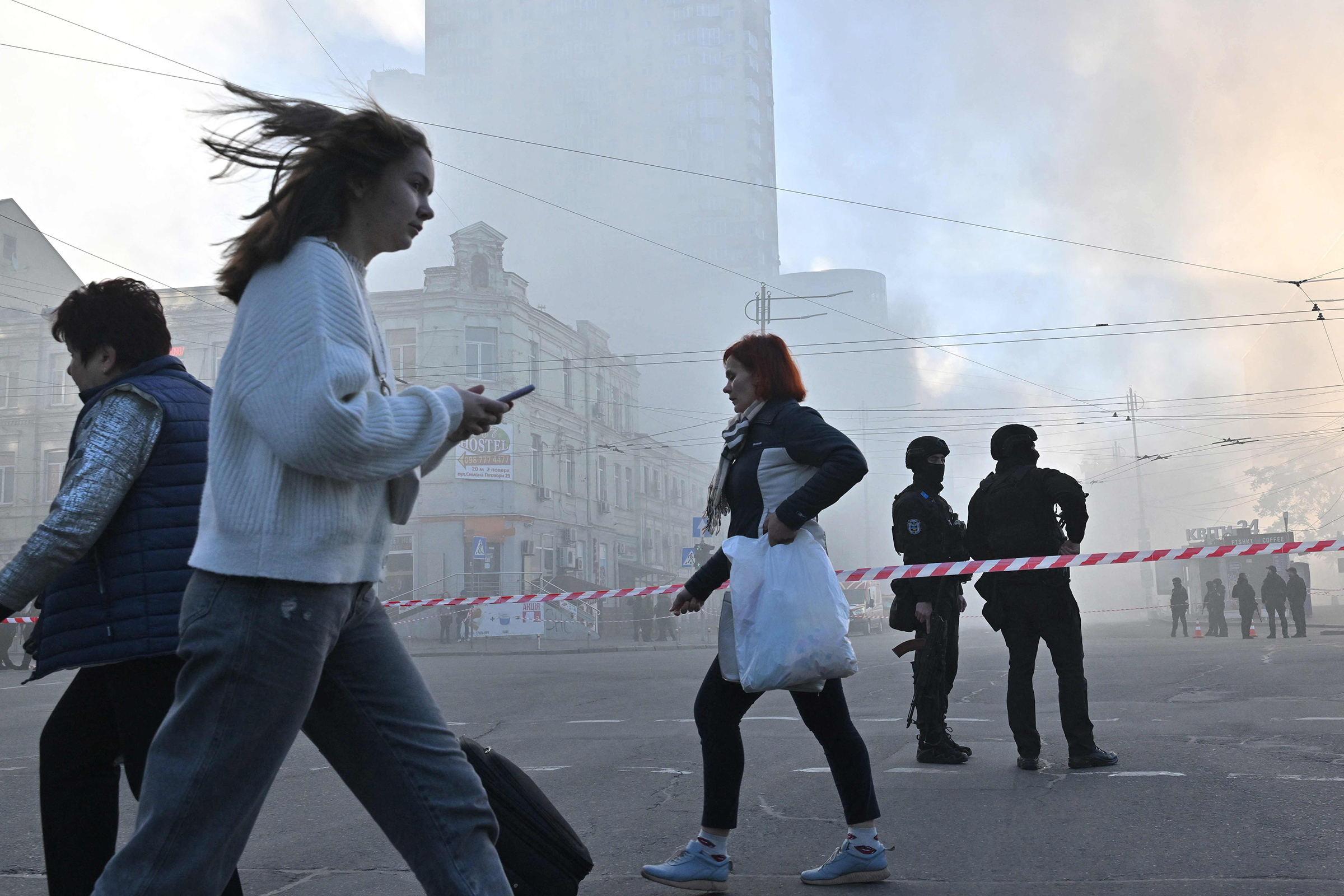 Local residents walk past police officers after a drone attack in Kyiv on Oct. 17 amid the Russian invasion of Ukraine.