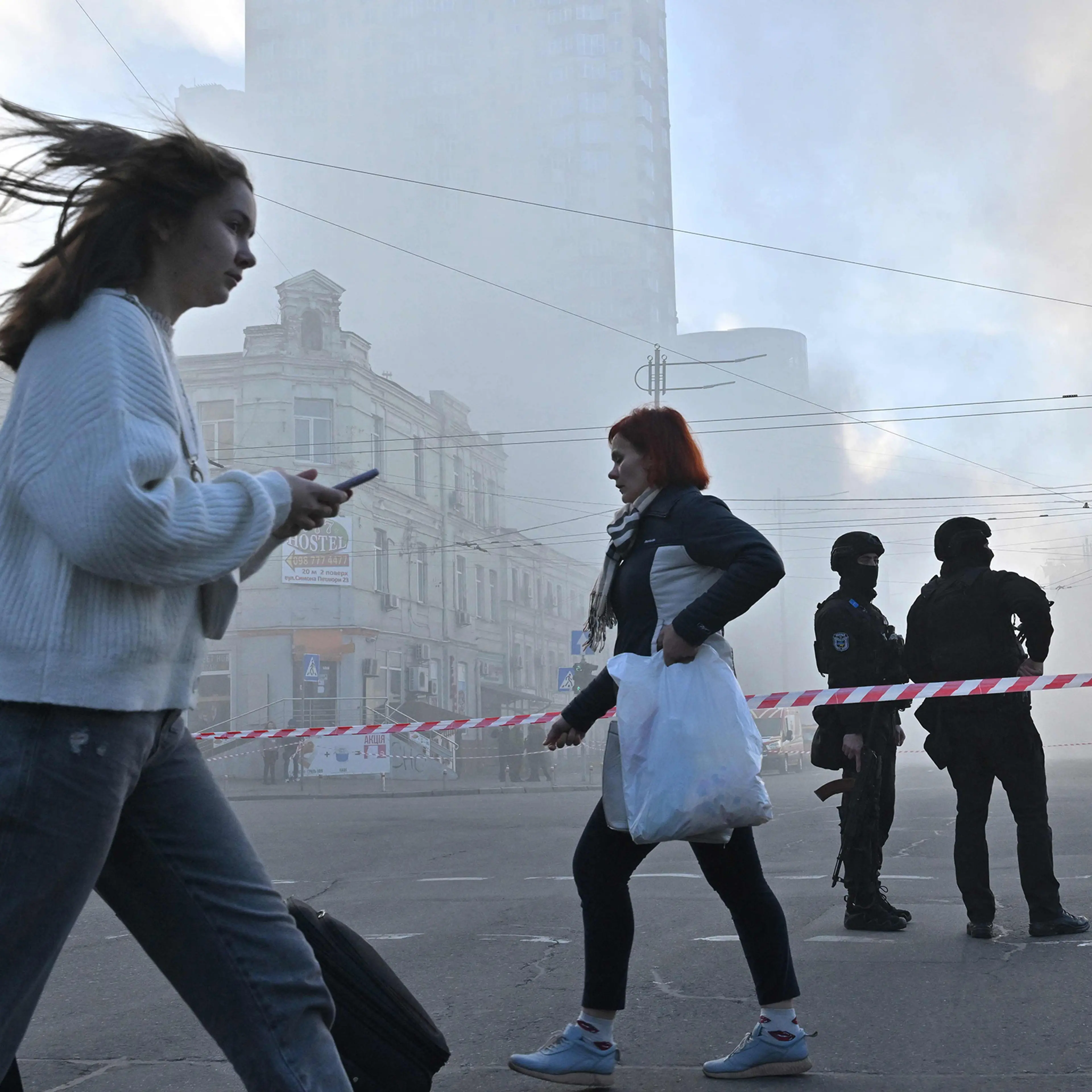 Local residents walk past police officers after a drone attack in Kyiv on Oct. 17 amid the Russian invasion of Ukraine.