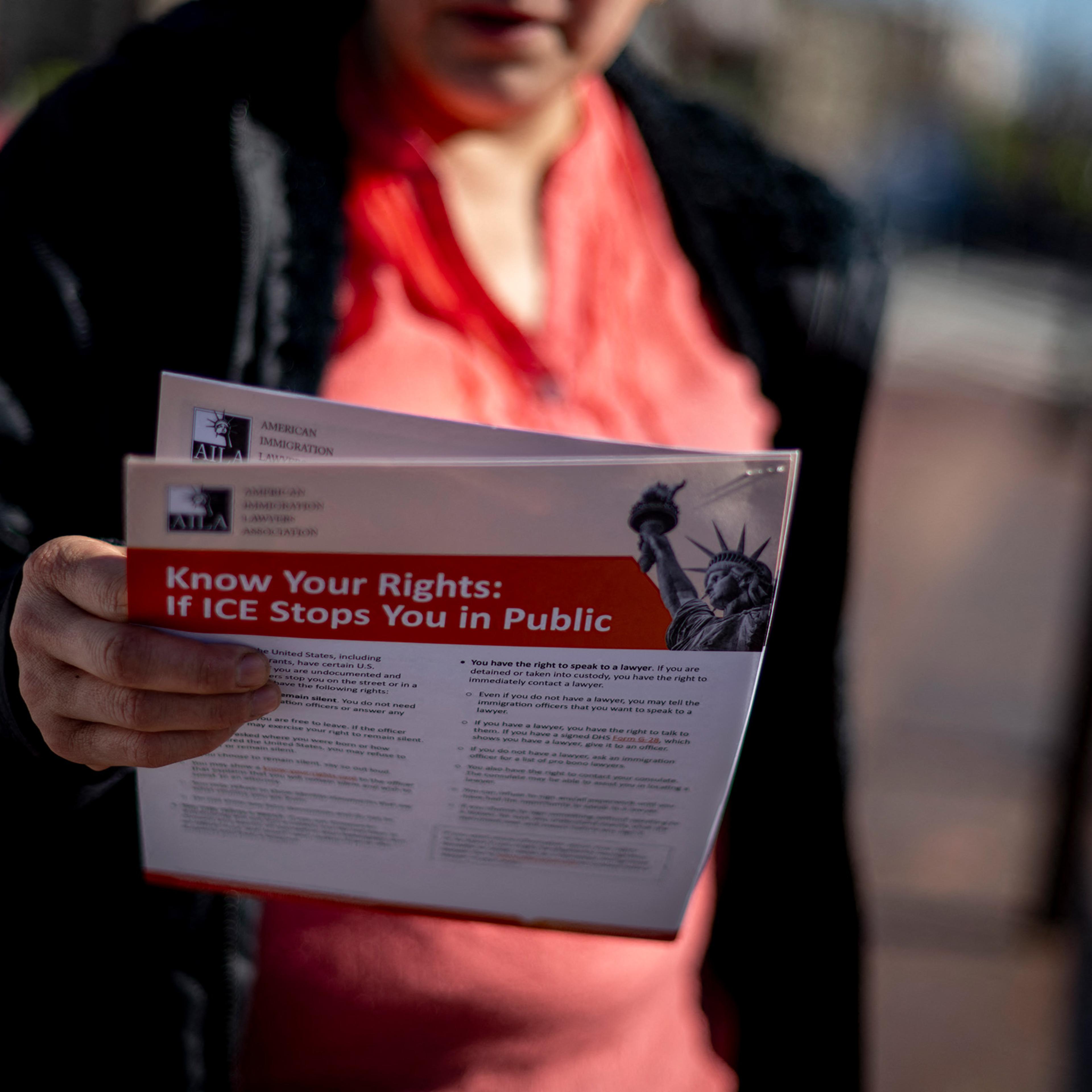 A woman reads a leaflet given to her by an immigration advocacy group containing information about immigrants' rights in a neighborhood in Washington, D.C., on March 21, 2025.