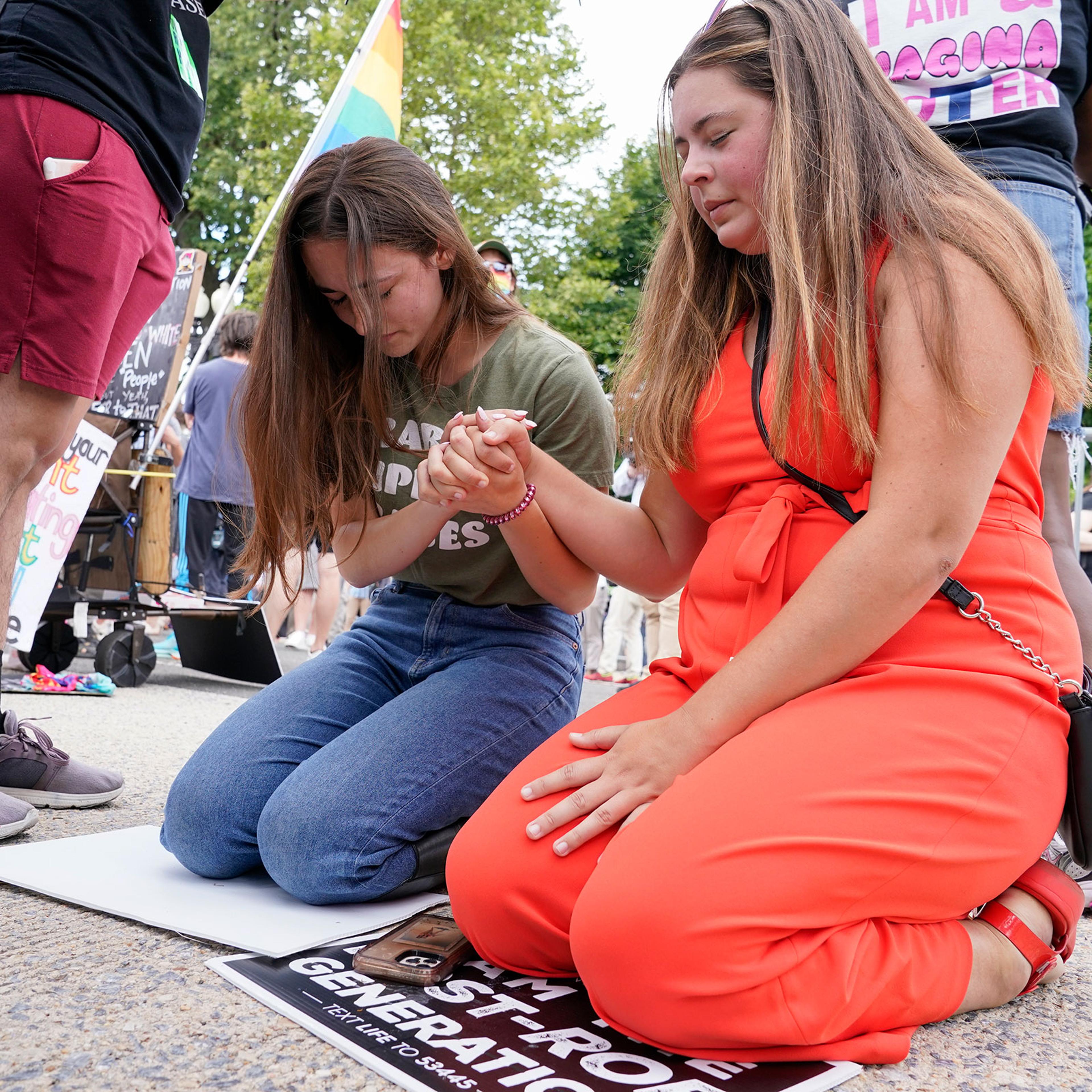 Anti-abortion activists Maggie Donica, 21, right, and Grace Rykaczewski, 21, left, pray following the Supreme Court's decision to overturn Roe v. Wade, federally protected right to abortion, in Washington, Friday, June 24, 2022.