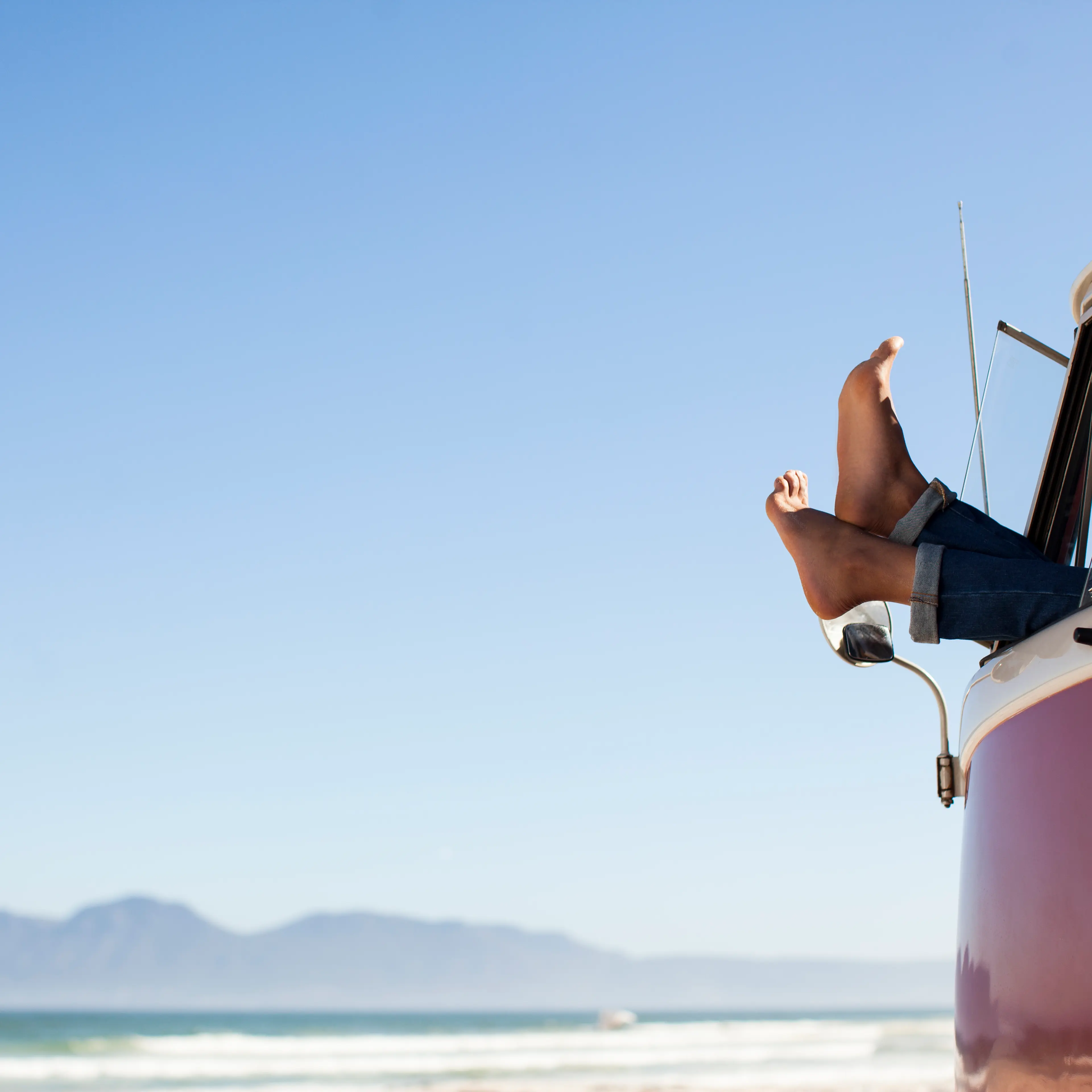 Feet sticking out of camper van window at beach