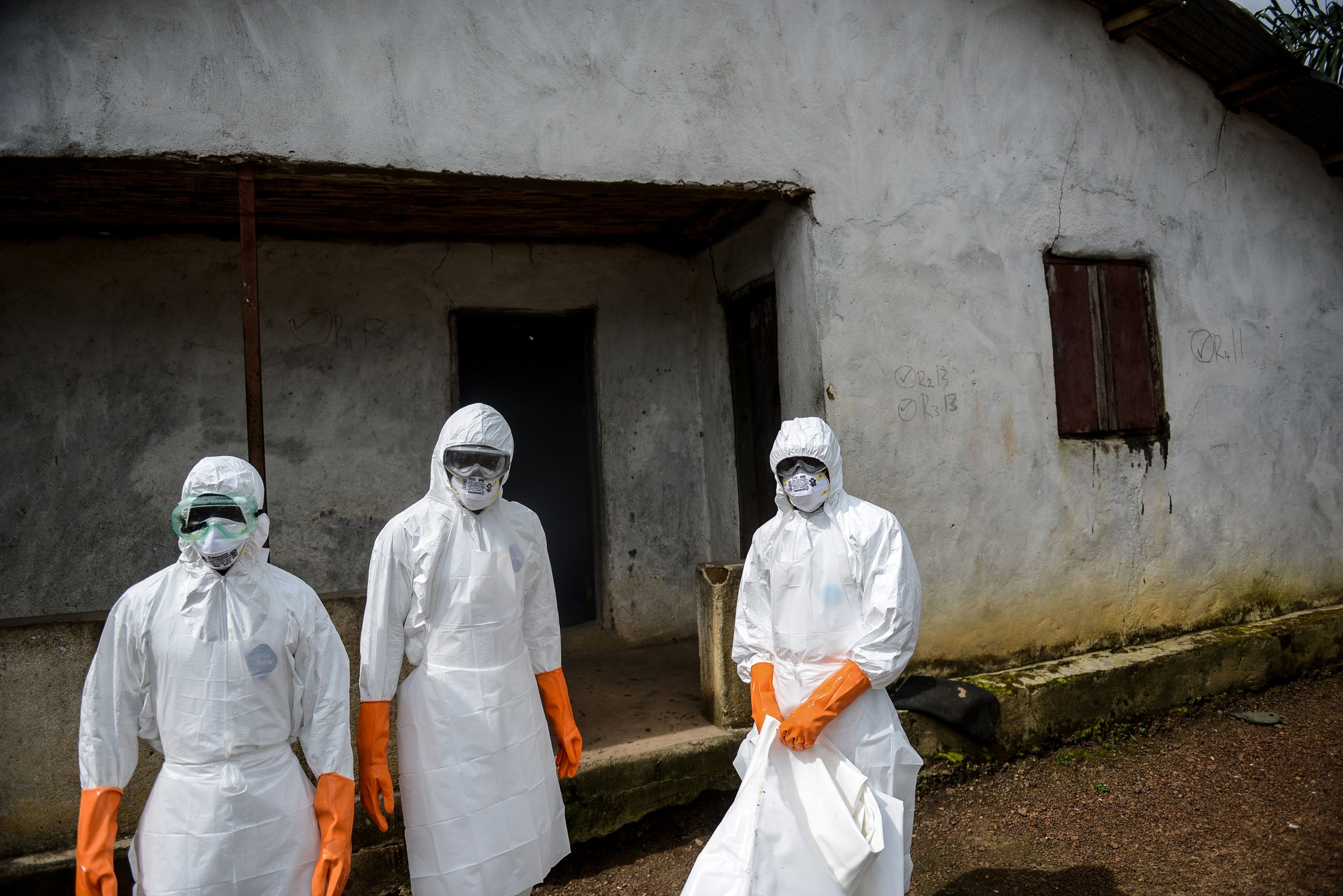 A group of young volunteers wear special uniforms sterilize round the house after Baindu Koruma (28) died due to the Ebola virus, in Lango village, Kenema, Sierra Leone on August 25, 2014.