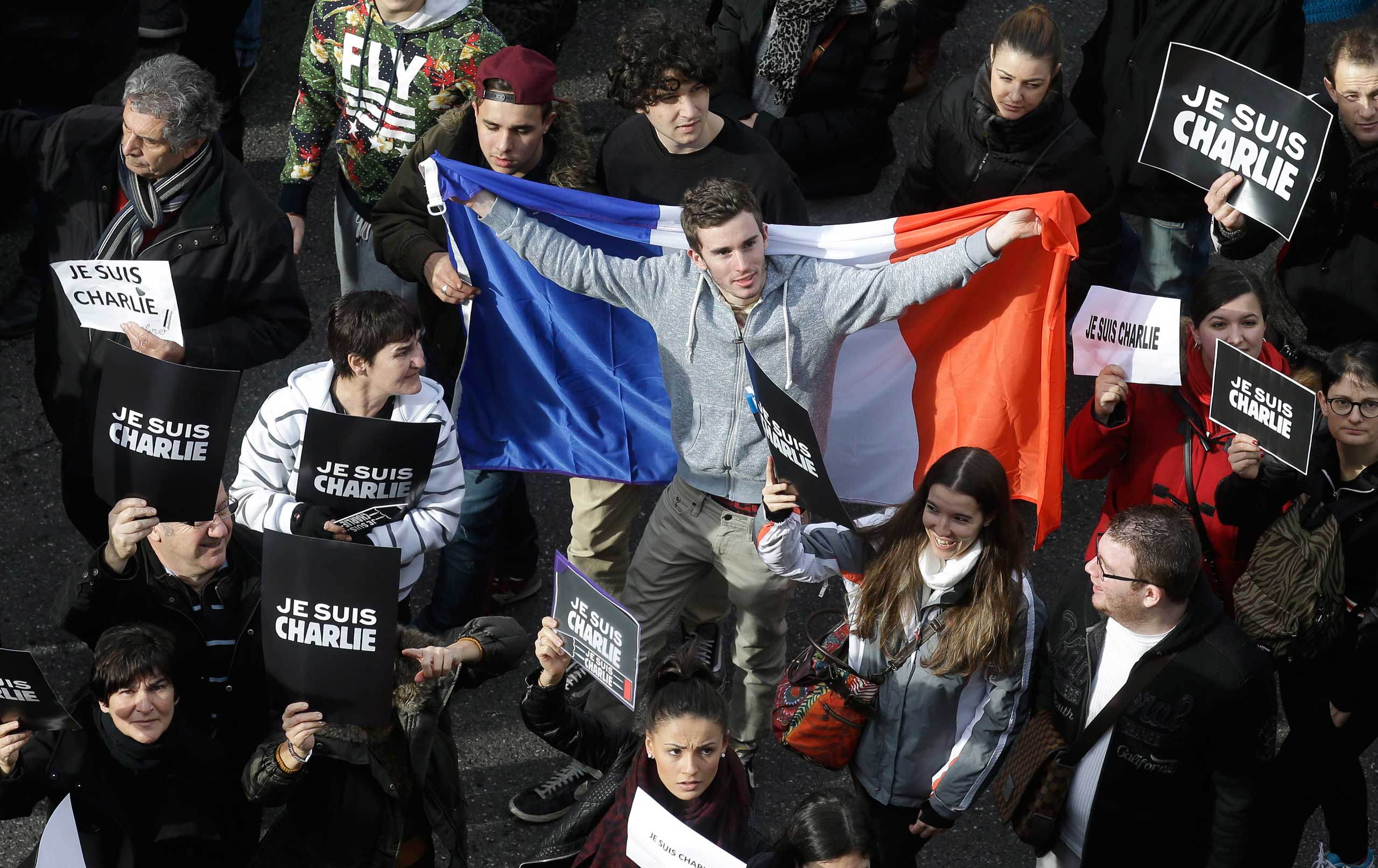 A man holds a French flag during a silent walk for victims of the shooting at the satirical newspaper Charlie Hebdo, Jan. 10, 2015, in Nice.