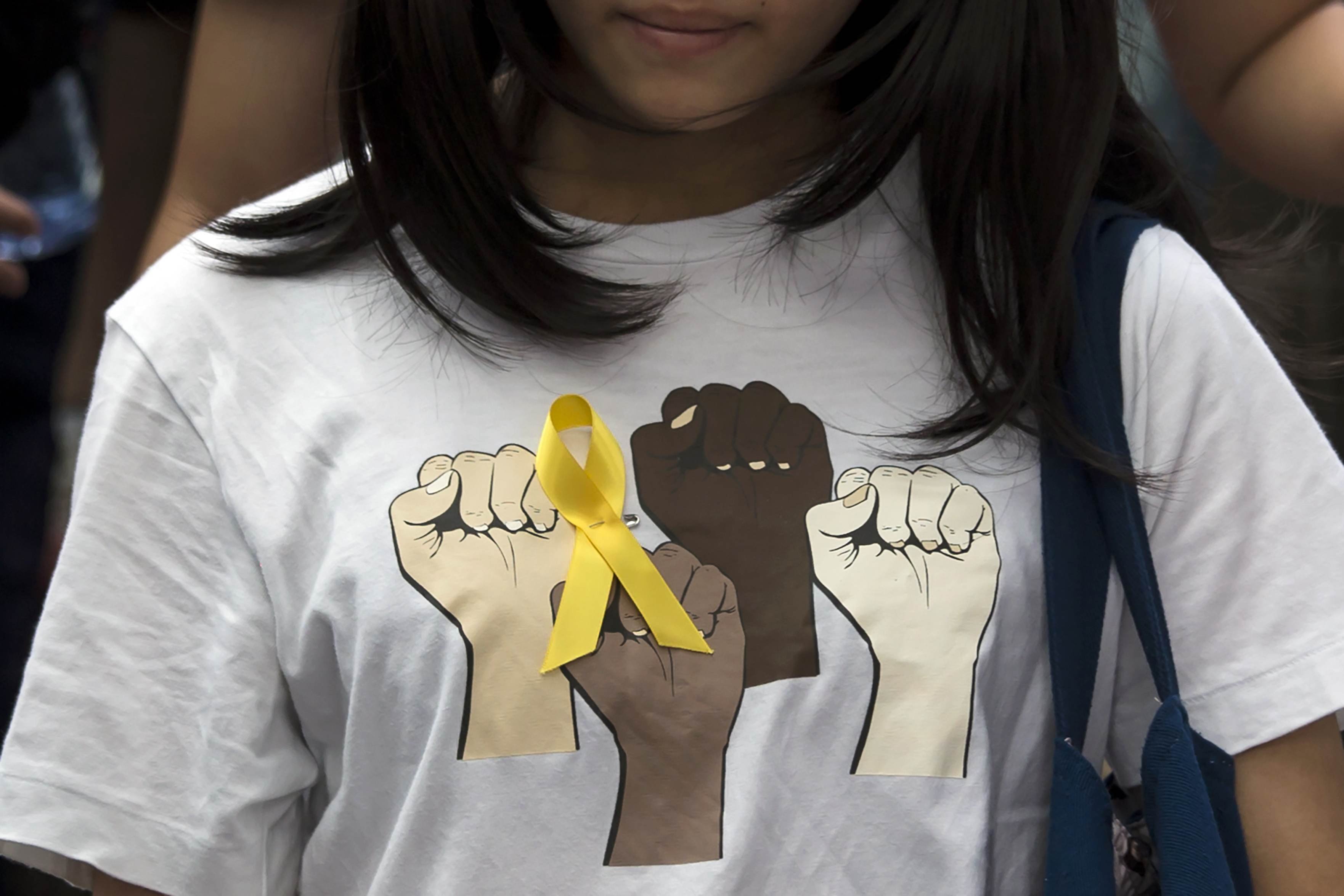 Secondary school student wears a yellow ribbon pinned to her T-shirt during a rally against Beijing's election framework for Hong Kong, outside the government headquarters in Hong Kong
