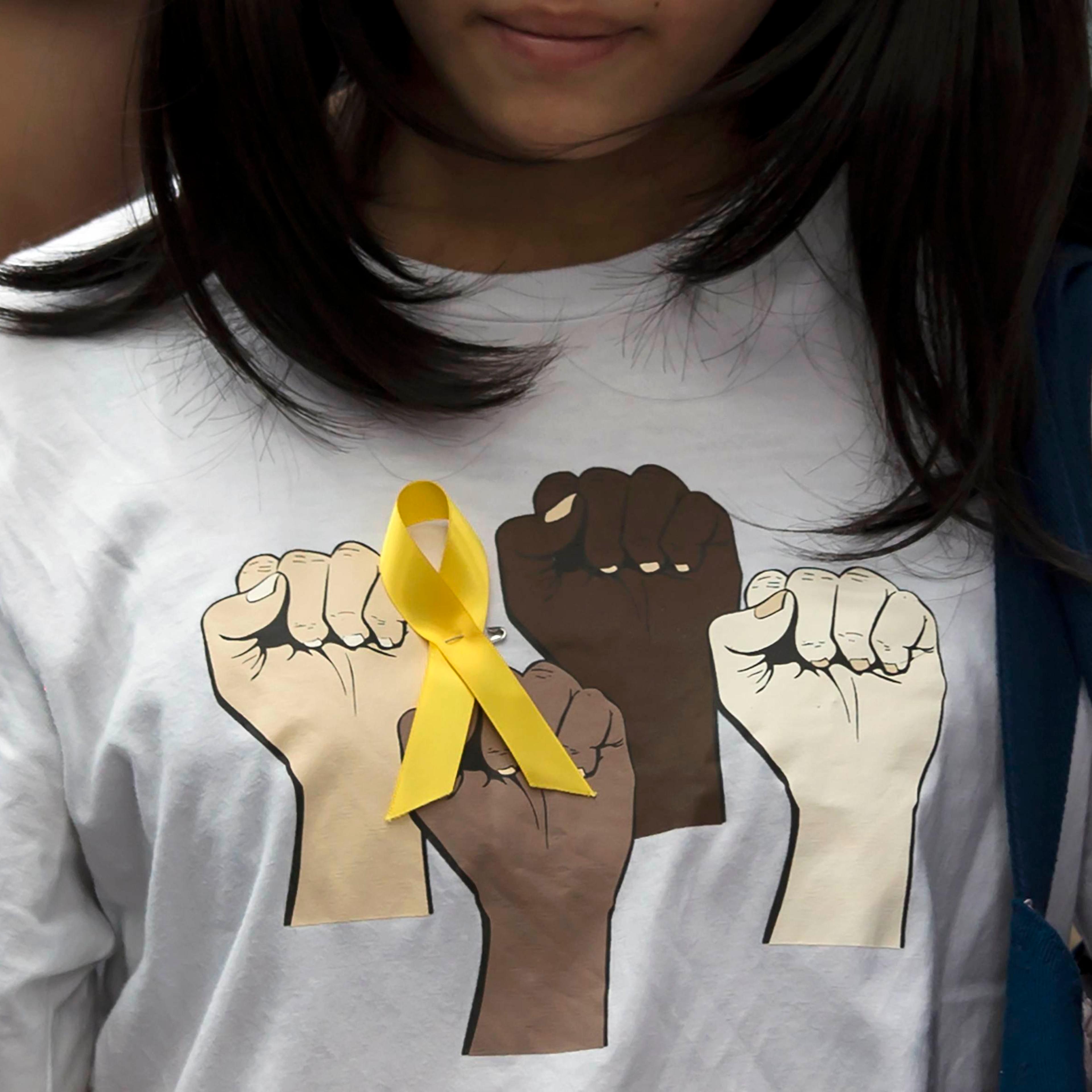 Secondary school student wears a yellow ribbon pinned to her T-shirt during a rally against Beijing's election framework for Hong Kong, outside the government headquarters in Hong Kong