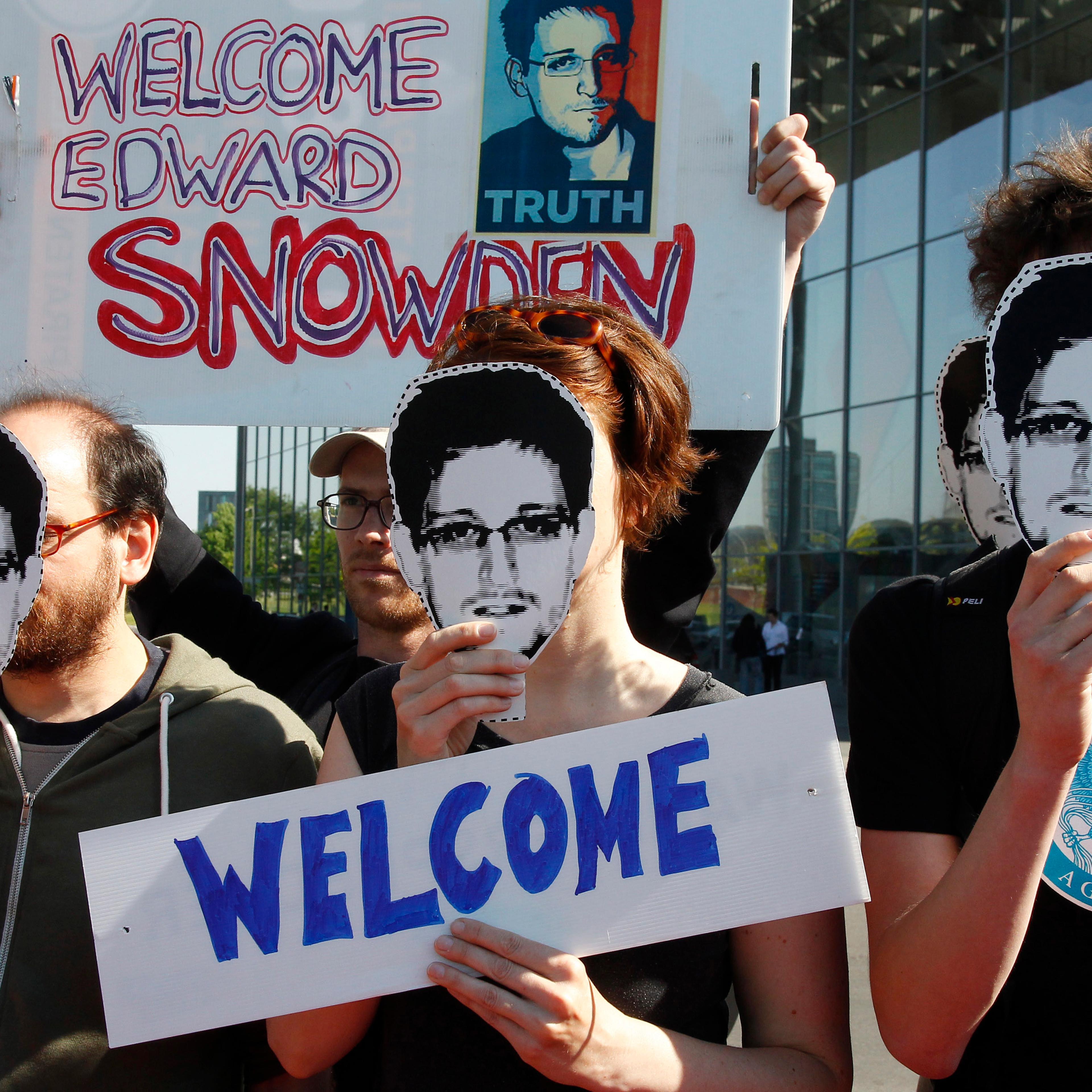 Protesters hold masks depicting Snowden during demonstration in Berlin
