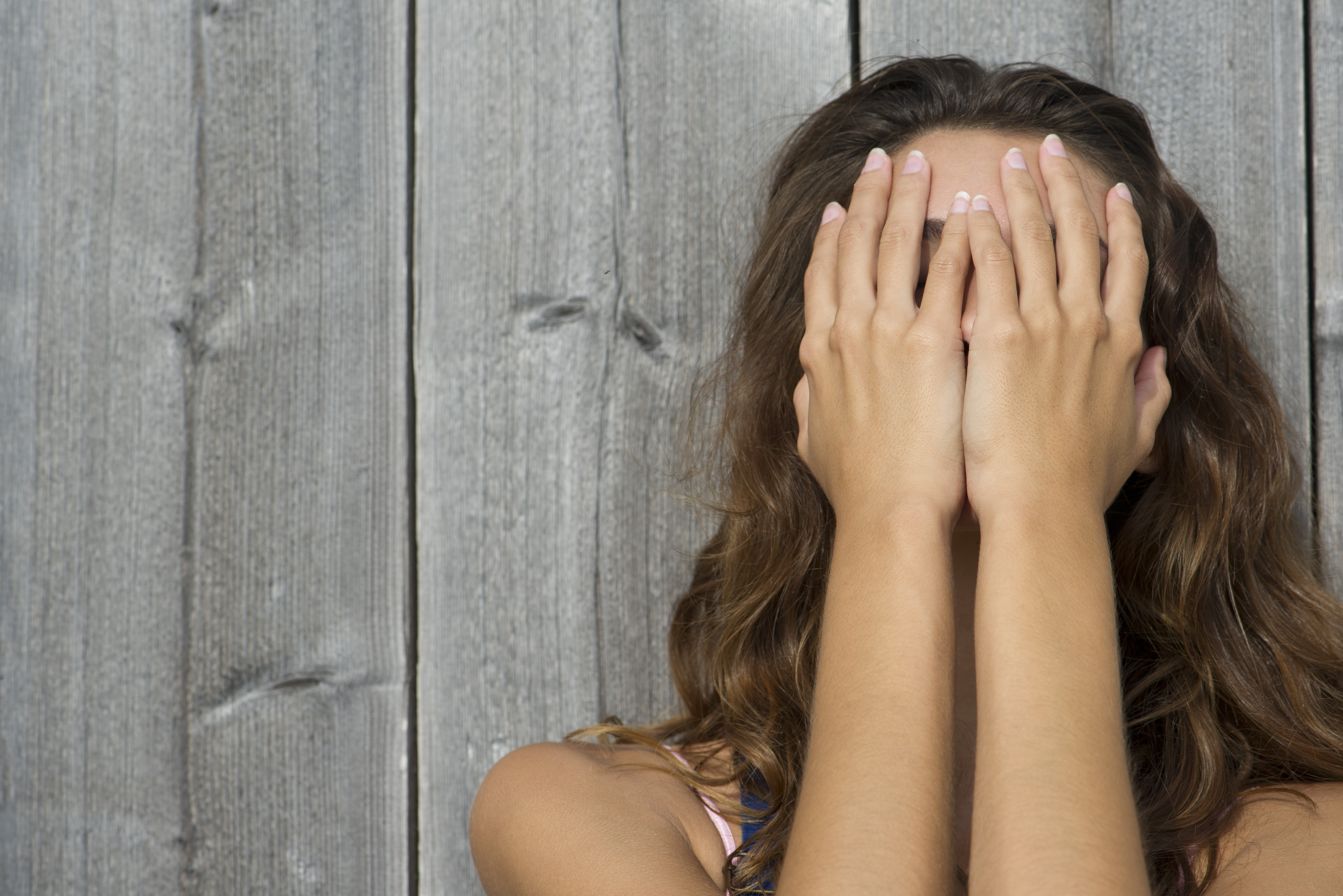 Young woman covering face with hands, portrait