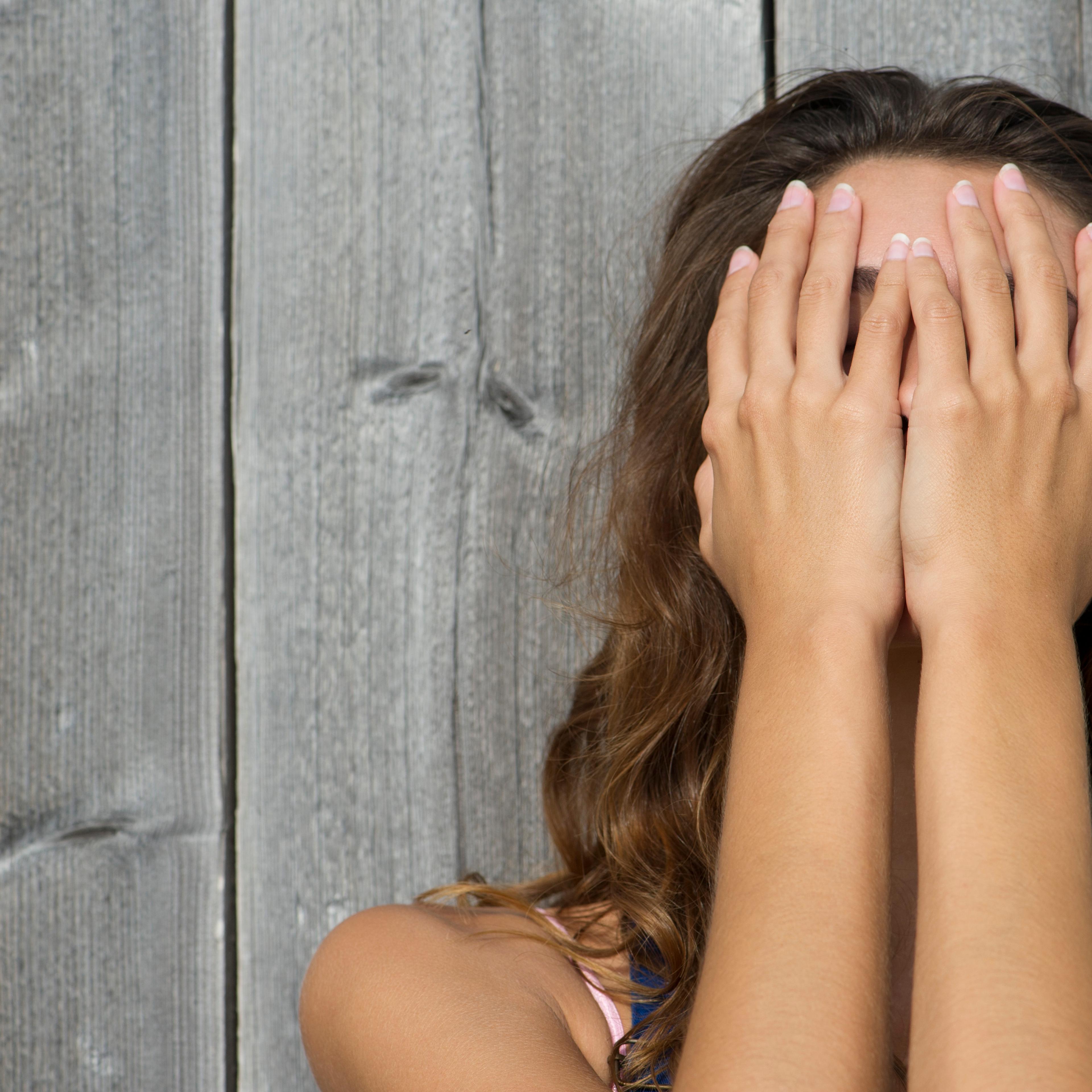 Young woman covering face with hands, portrait