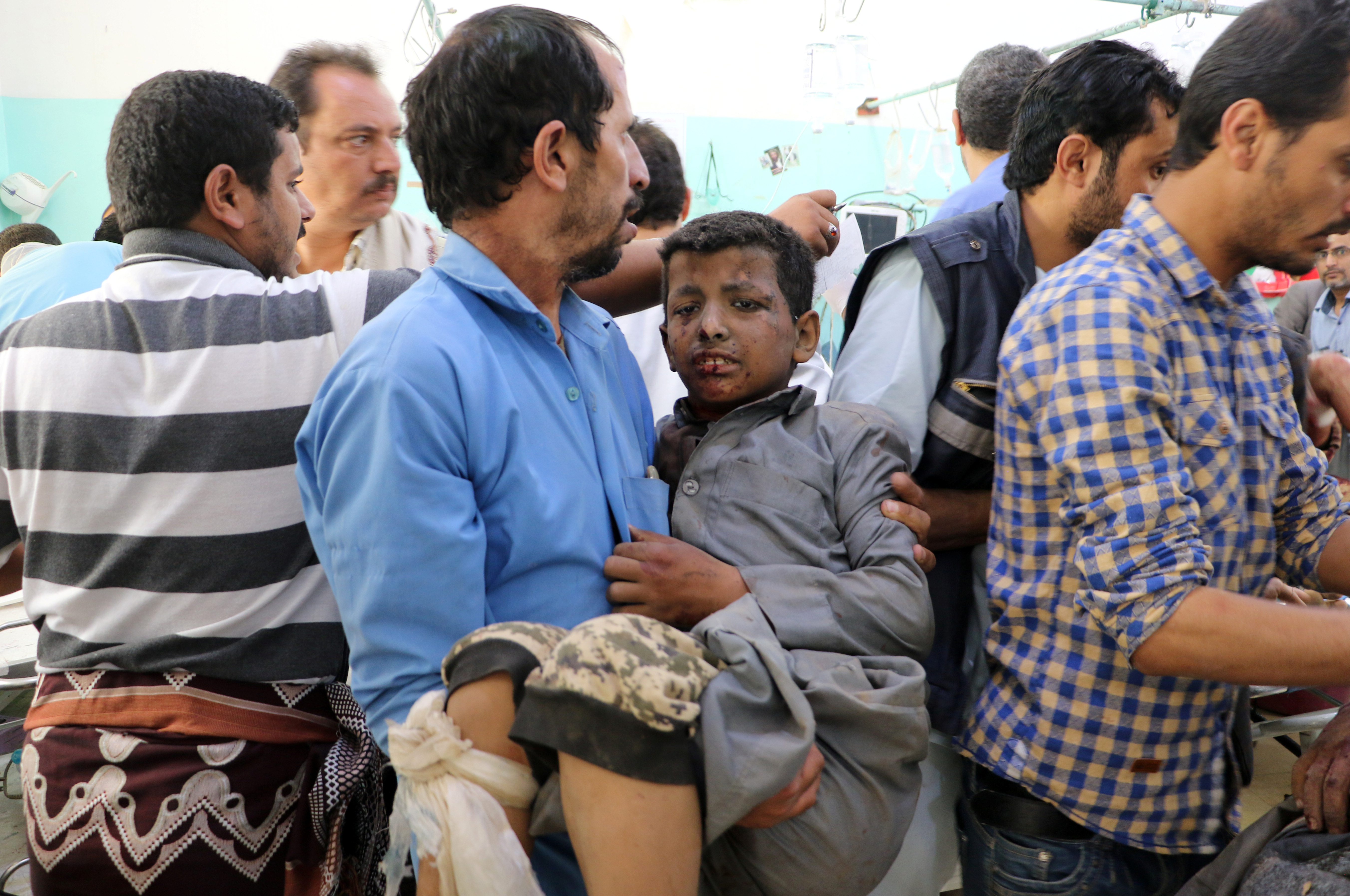 A Yemeni man holds a boy who was injured by an airstrike in Saada
