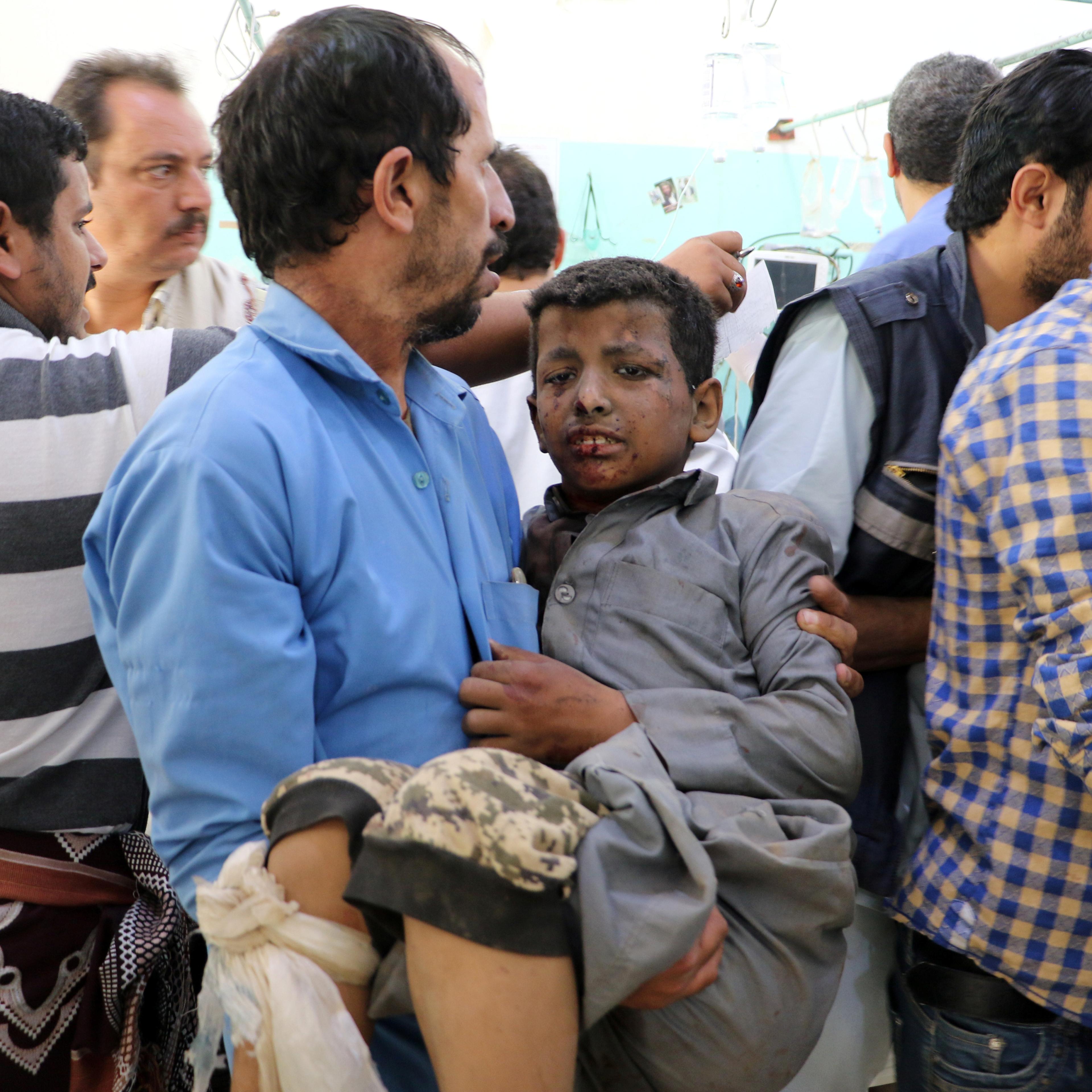 A Yemeni man holds a boy who was injured by an airstrike in Saada