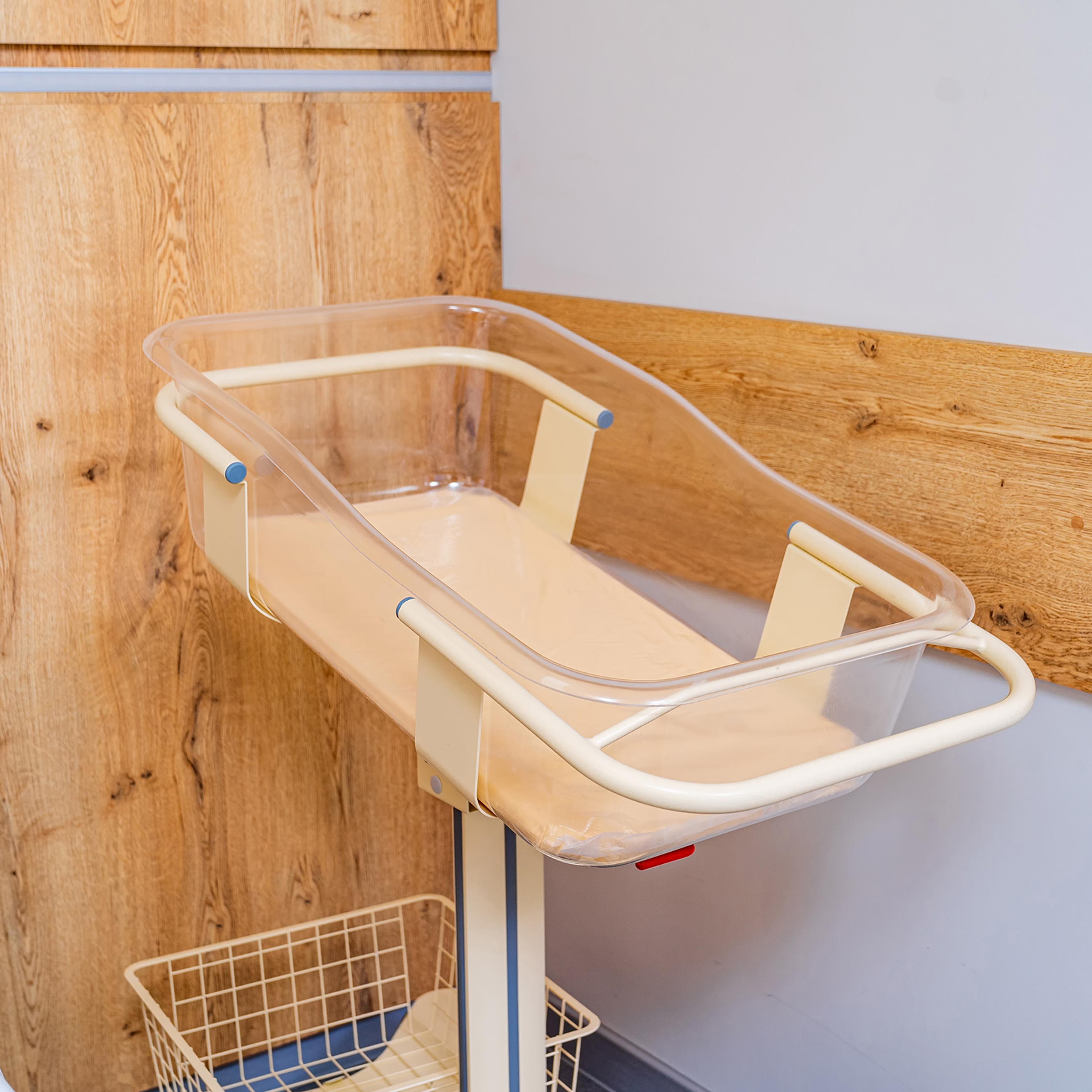 Closeup of an empty baby cradle in the postpartum ward of a hospital.