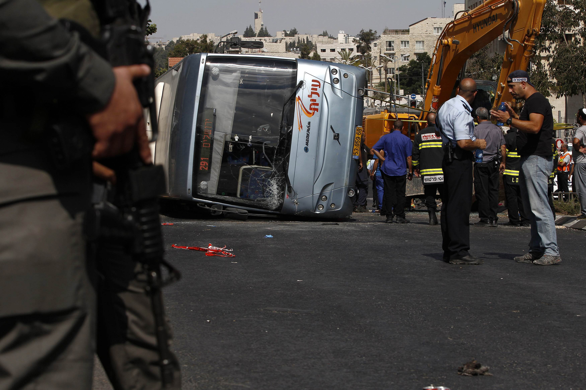 Israeli policemen stand next to an overturned bus at the scene of a suspected attack in Jerusalem, Aug. 4, 2014.