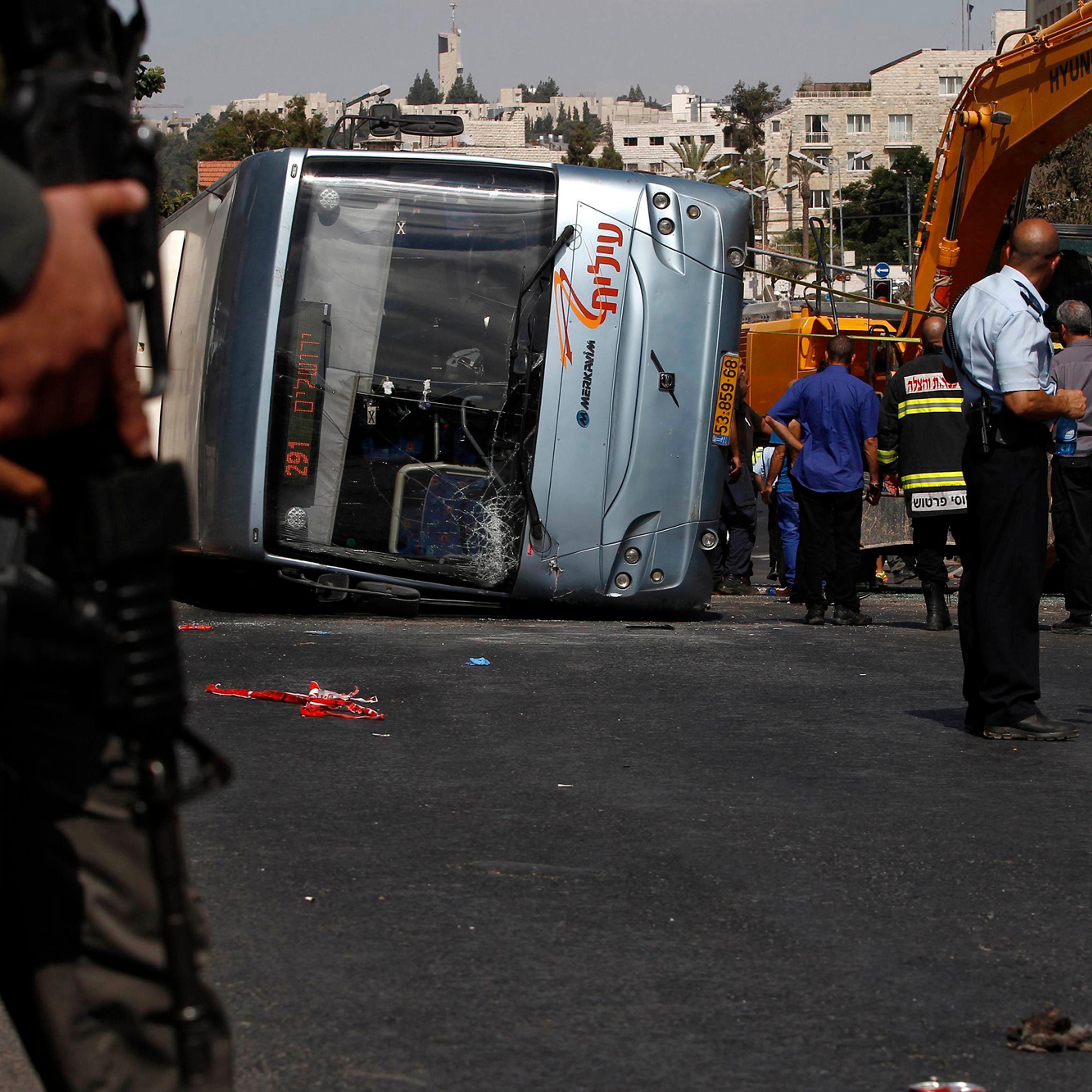 Israeli policemen stand next to an overturned bus at the scene of a suspected attack in Jerusalem, Aug. 4, 2014.