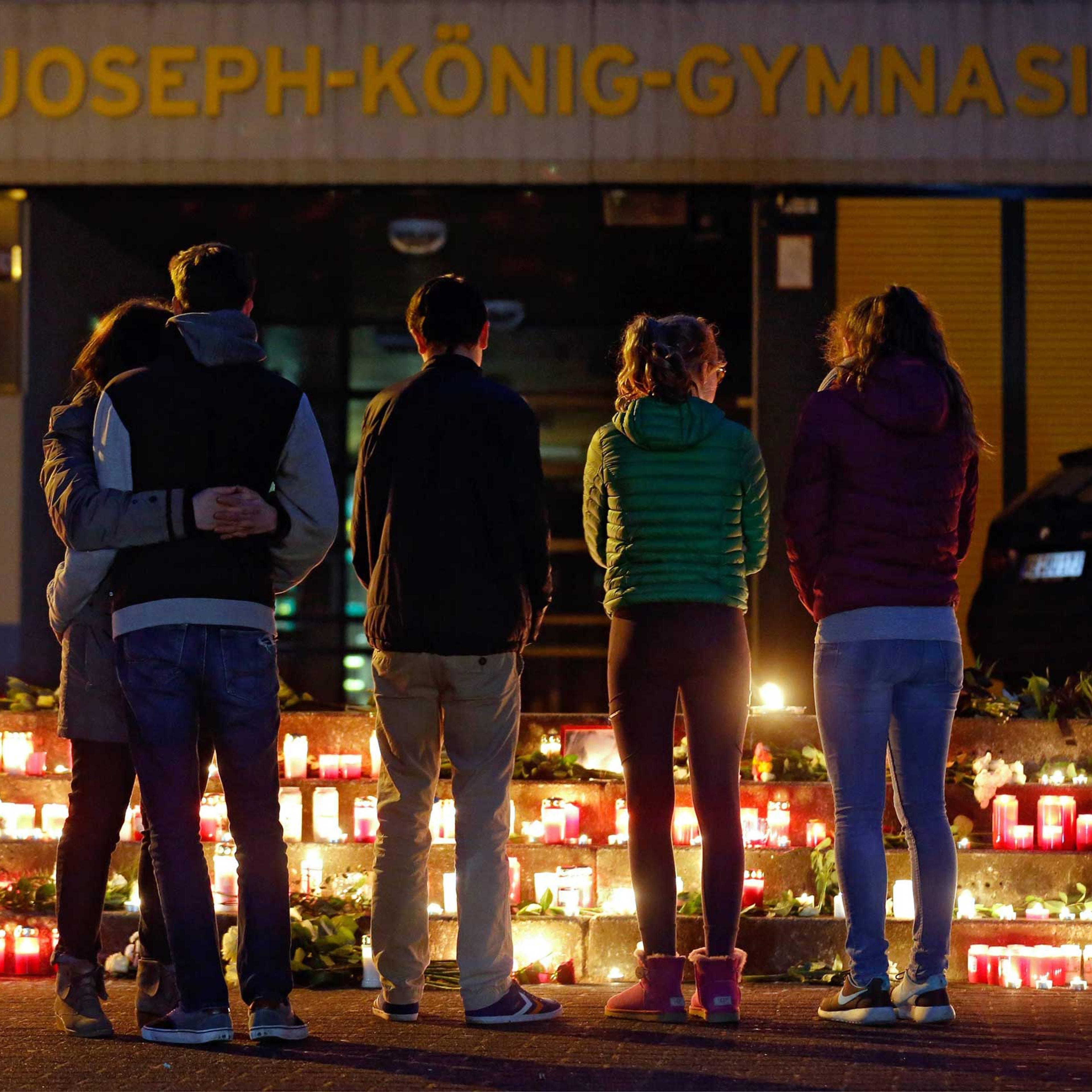 People stand in front of candles and flowers placed in front of the Joseph-Koenig-Gymnasium in Haltern, Germany, March 24, 2015.