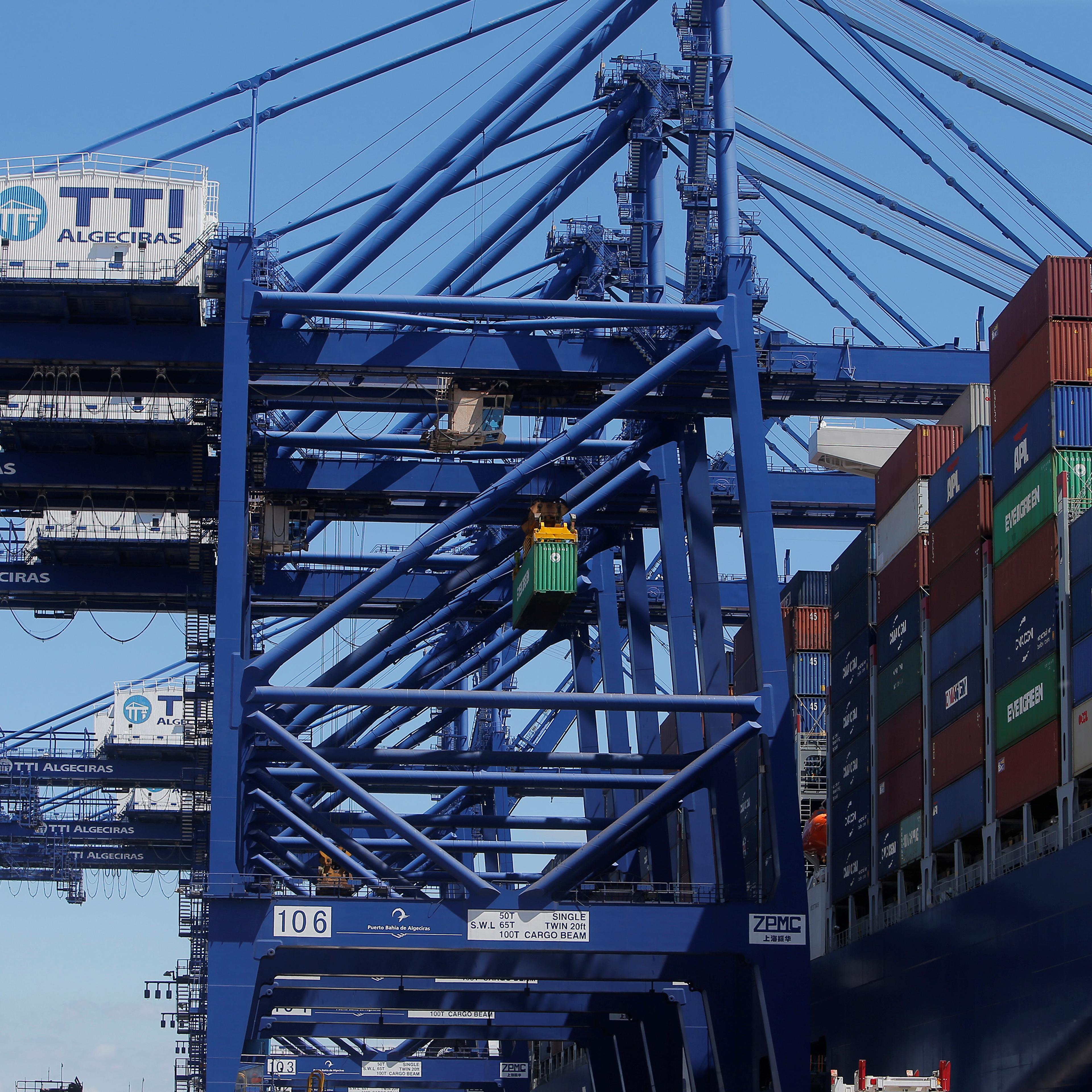 A crane loads a container on the mega cargo ship "Antoine de Saint Exupery" at the Total Terminal International Algeciras before leaving the port of Algeciras